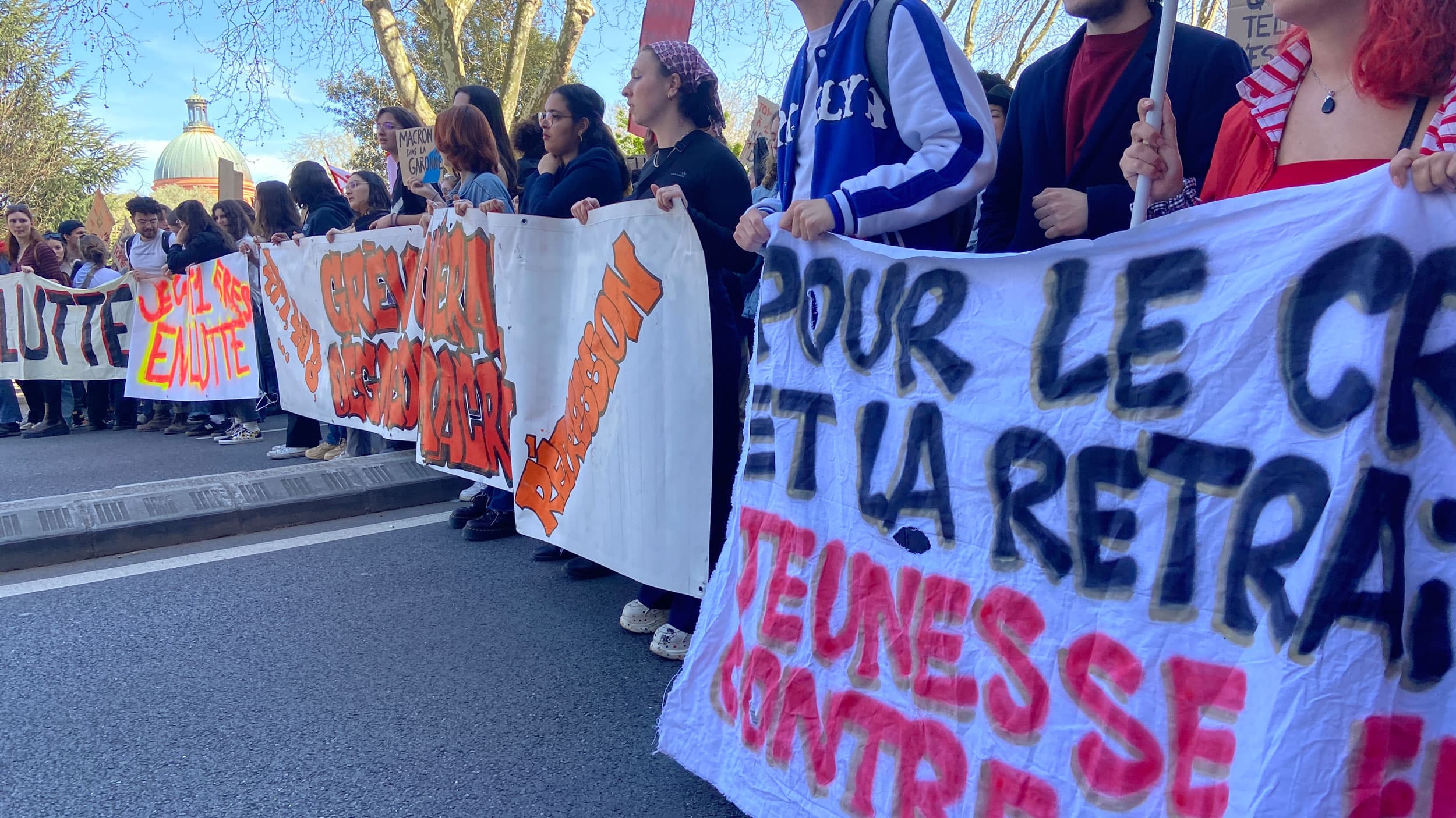 Michelie helps carry a banner at the Toulouse protest. It reads, “Youth against raising the retirement age.”
