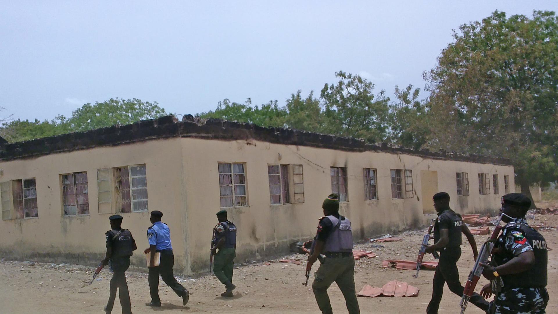 Security officers walk past a burnt-out government secondary school in Chibok in April 2014, where gunmen abducted more than 200 students.
