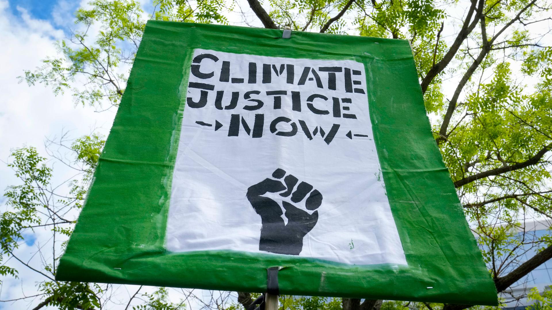 A sign is displayed as demonstrators protest about climate change outside of the IMF and World Bank Spring Meetings, Friday, April 14, 2023, in Washington.