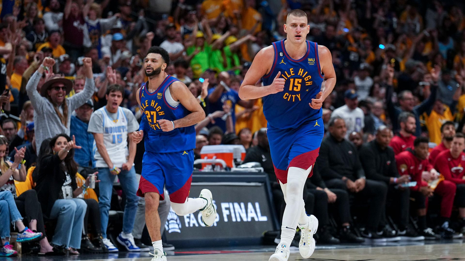 Denver Nuggets center Nikola Jokić, right, jogs on the court during the second half of Game 1 of basketball's NBA Finals against the Miami Heat, Thursday, June 1, 2023, in Denver.