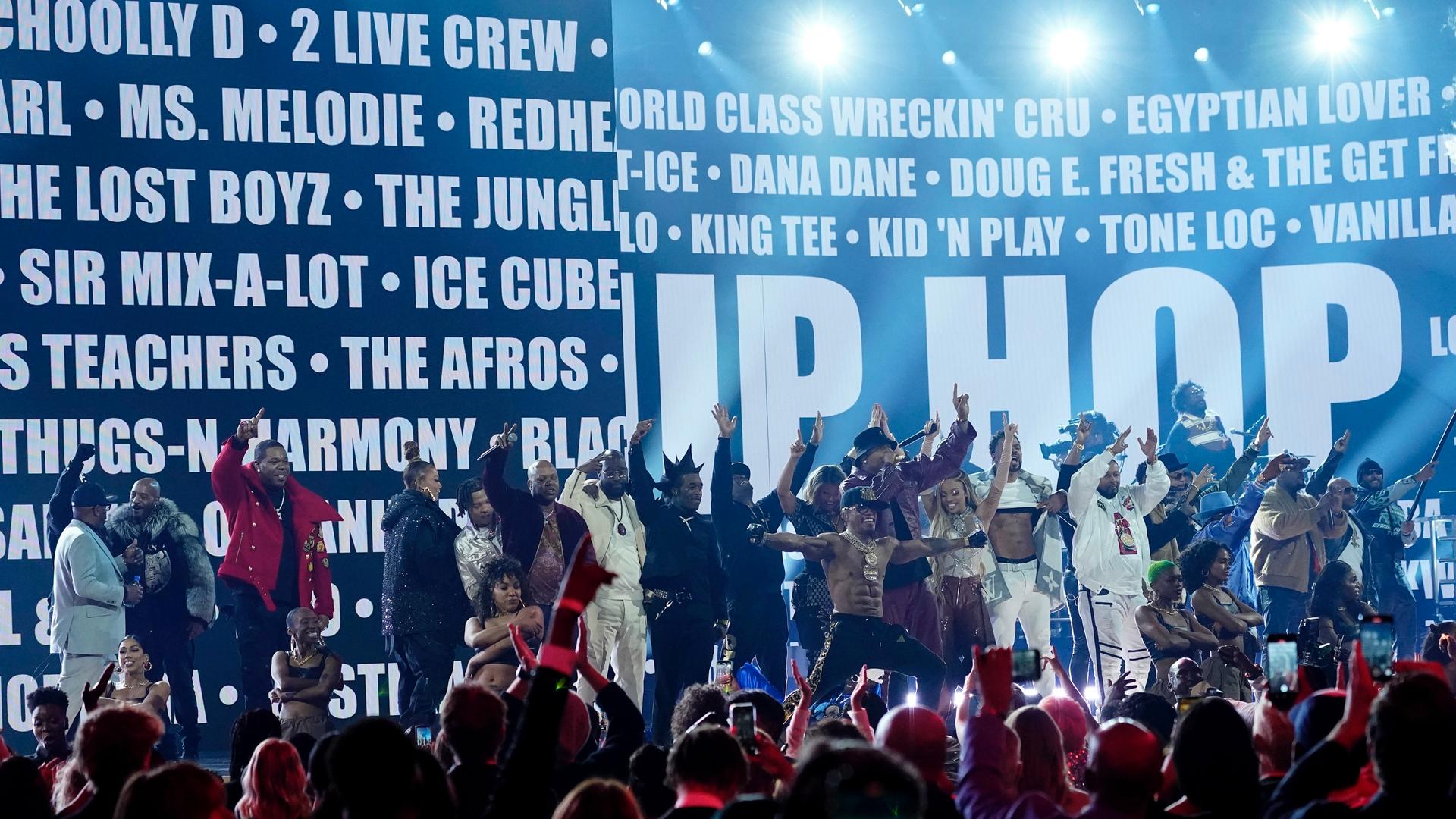 Photo of hip hop artists on stage with a crowd cheering them on