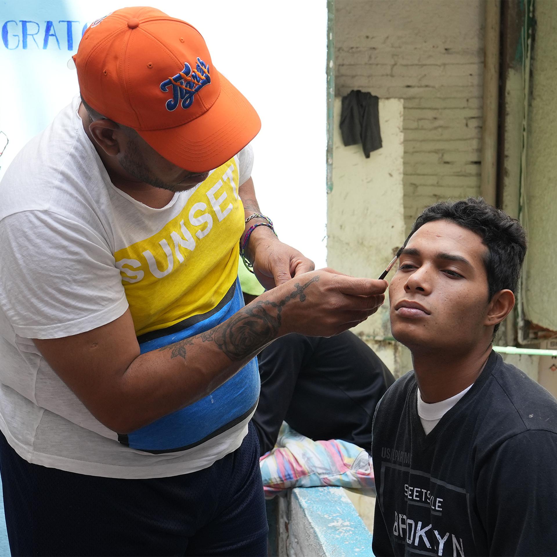 A Venezuelan migrant helps a migrant from El Salvador to trim his eyebrows at the Casa Tochan shelter in Mexico City.