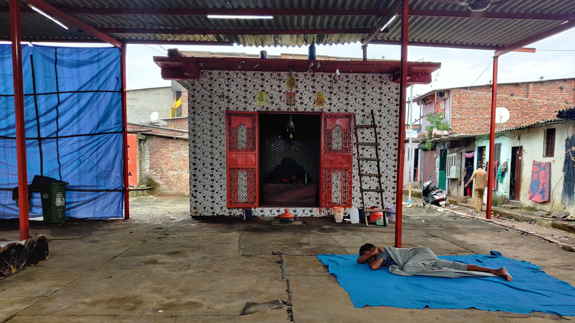 a man sleeping on the ground outside of a temple