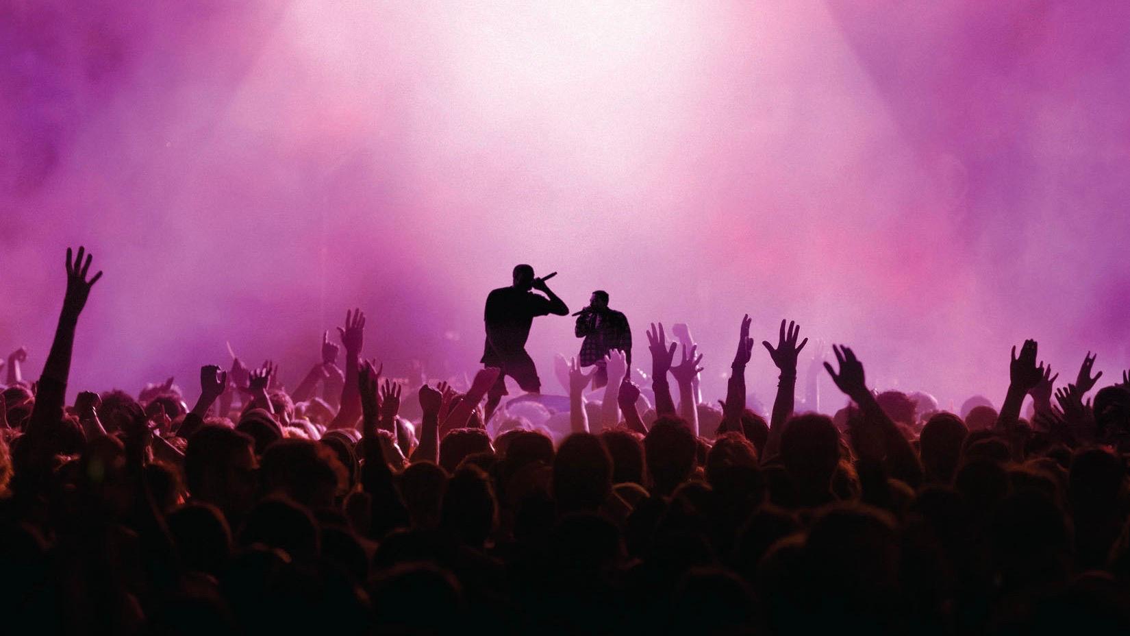 Maroon silhouette of two people performing in front of a crowd of people