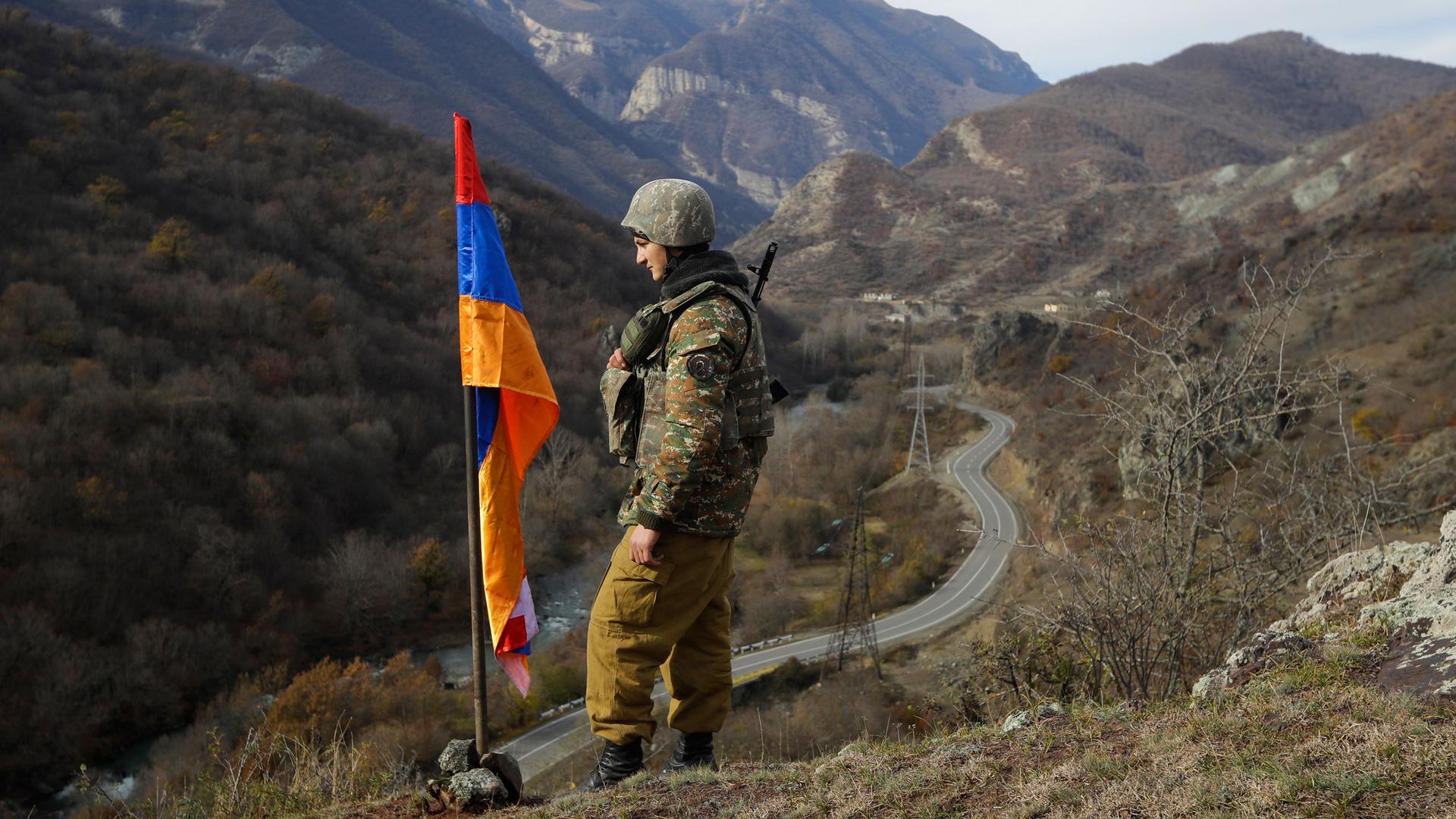 In this Wednesday, Nov. 25, 2020, file photo, an ethnic Armenian soldier stands guard next to Nagorno-Karabakh's flag atop of the hill near Charektar in the separatist region of Nagorno-Karabakh, at a new border with Kalbajar district turned over to Azerb