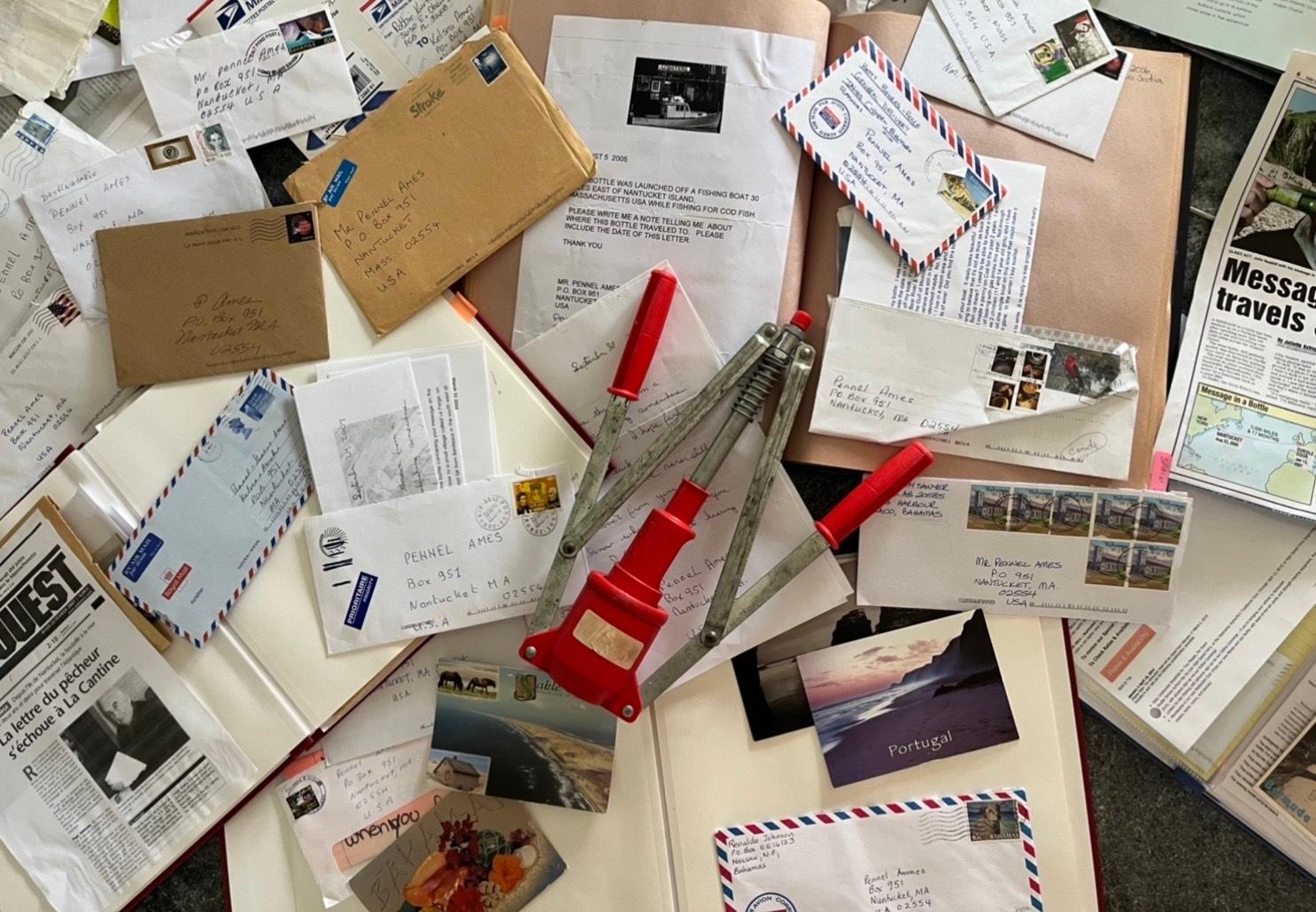 A handheld bottle corker rests on top of scrapbooks of letters, postcards, emails and press clippings of people who found bottles thrown by Pennel Ames into the ocean.