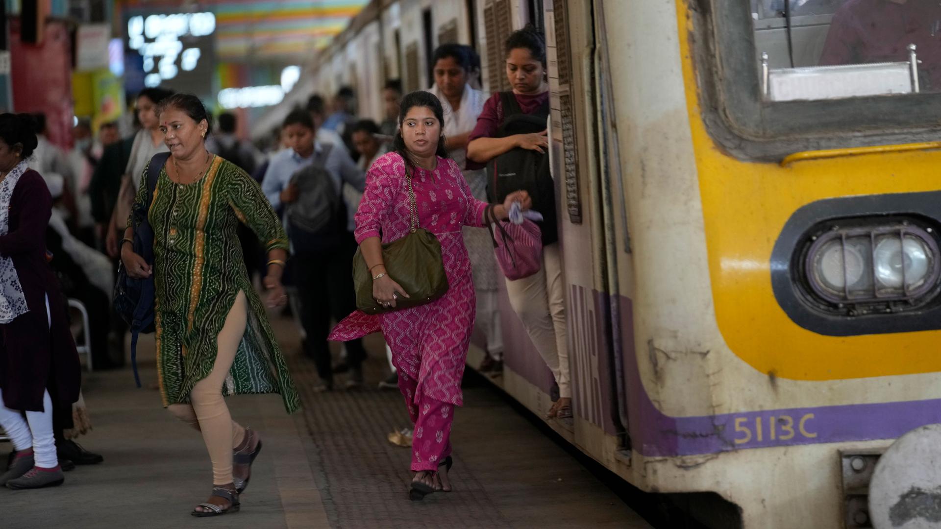 Women rush out of a train during peak hours at Churchgate station in Mumbai, India, Monday, March 20, 2023. 