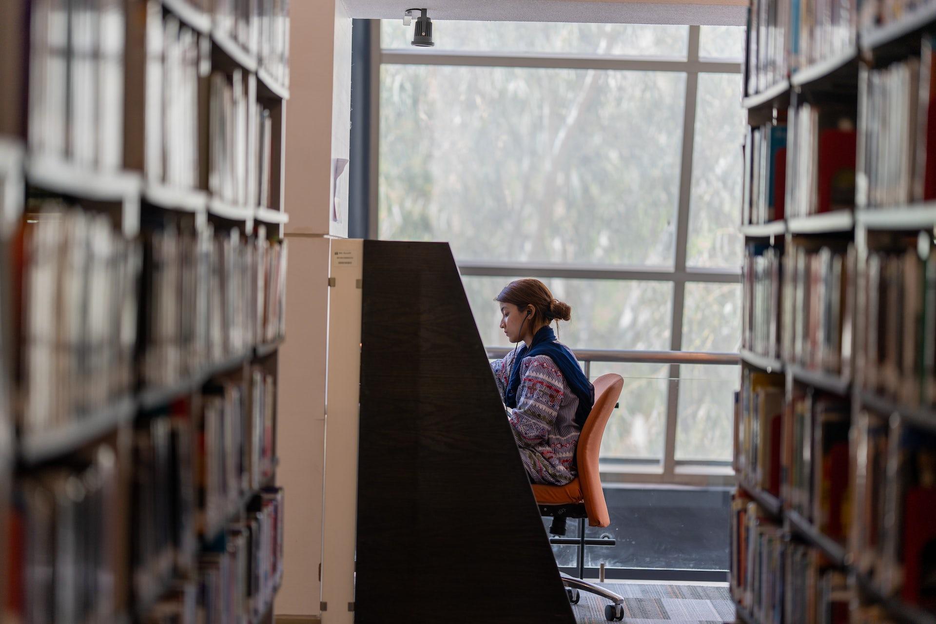 A woman working at a carrel in library stacks
