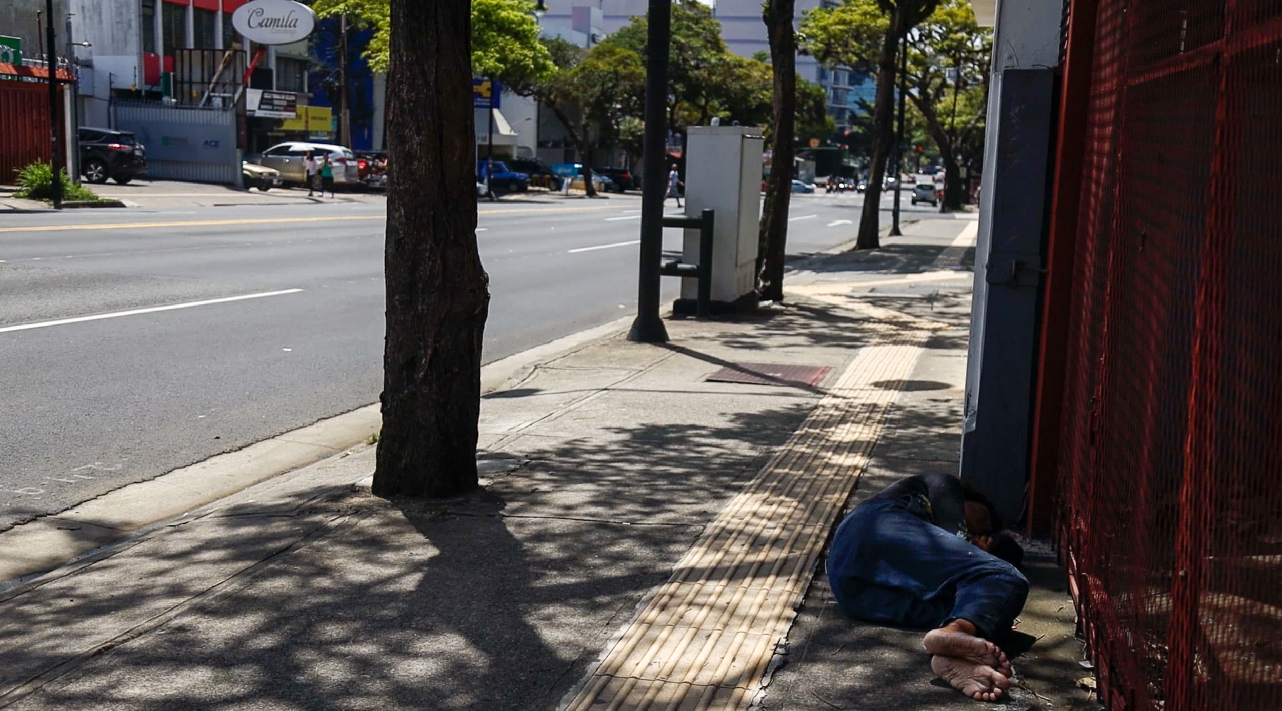 A man is lying in the streets of downtown San Jose, Costa Rica.