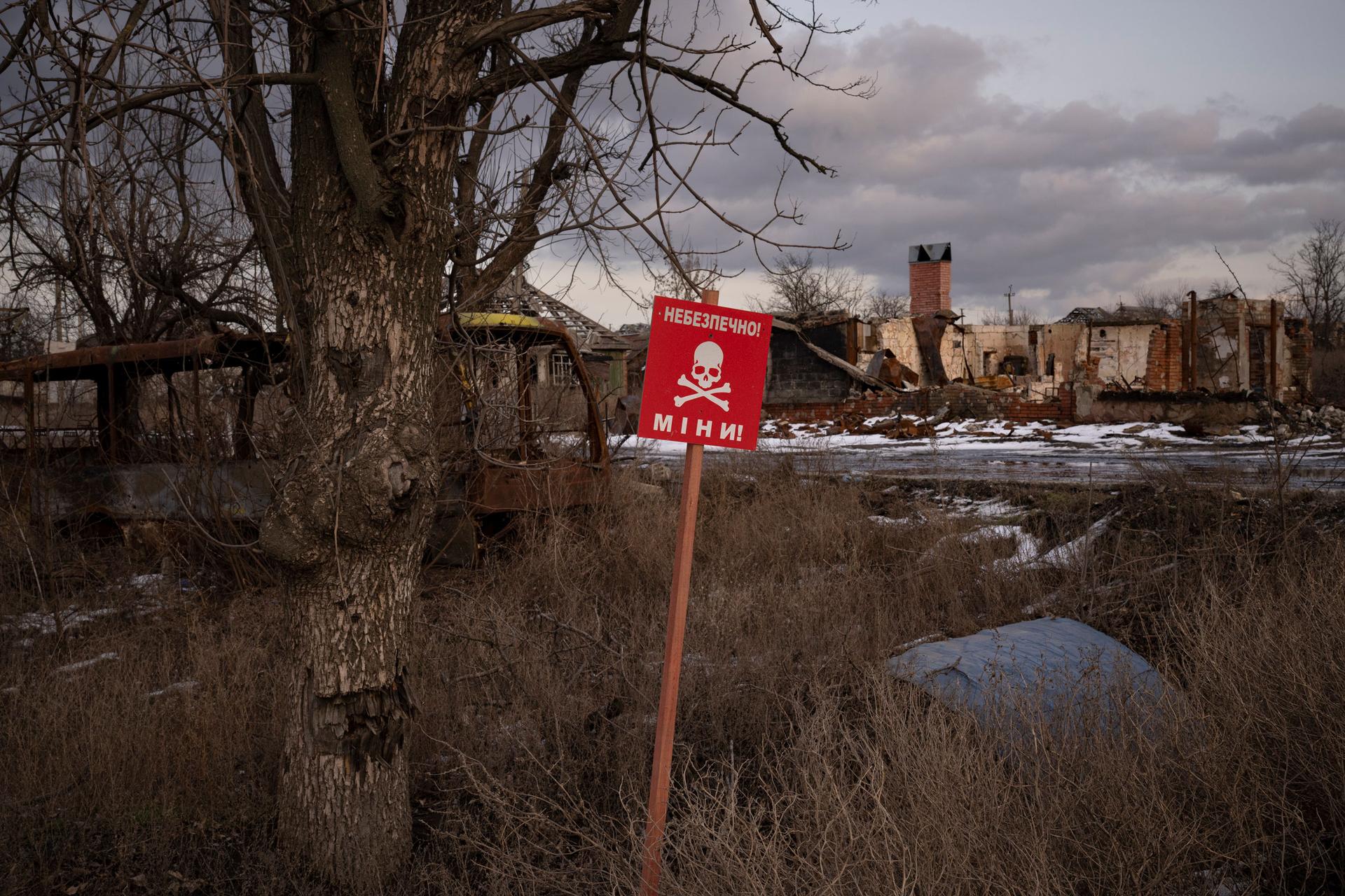 A sign that reads "Mines" is placed on the site of the road in the village of Kamyanka, on the outskirts of Izium, Ukraine, Sunday, Feb. 19, 2023. 