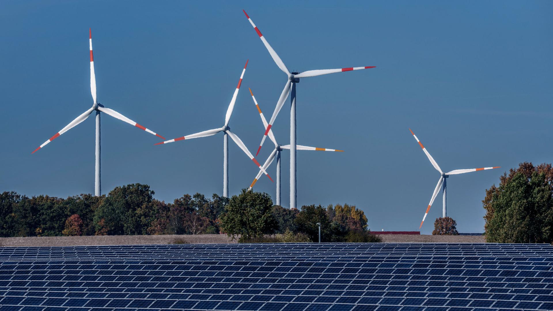 Wind turbines turn behind a solar farm in Rapshagen, Germany, Thursday, Oct. 28, 2021. 