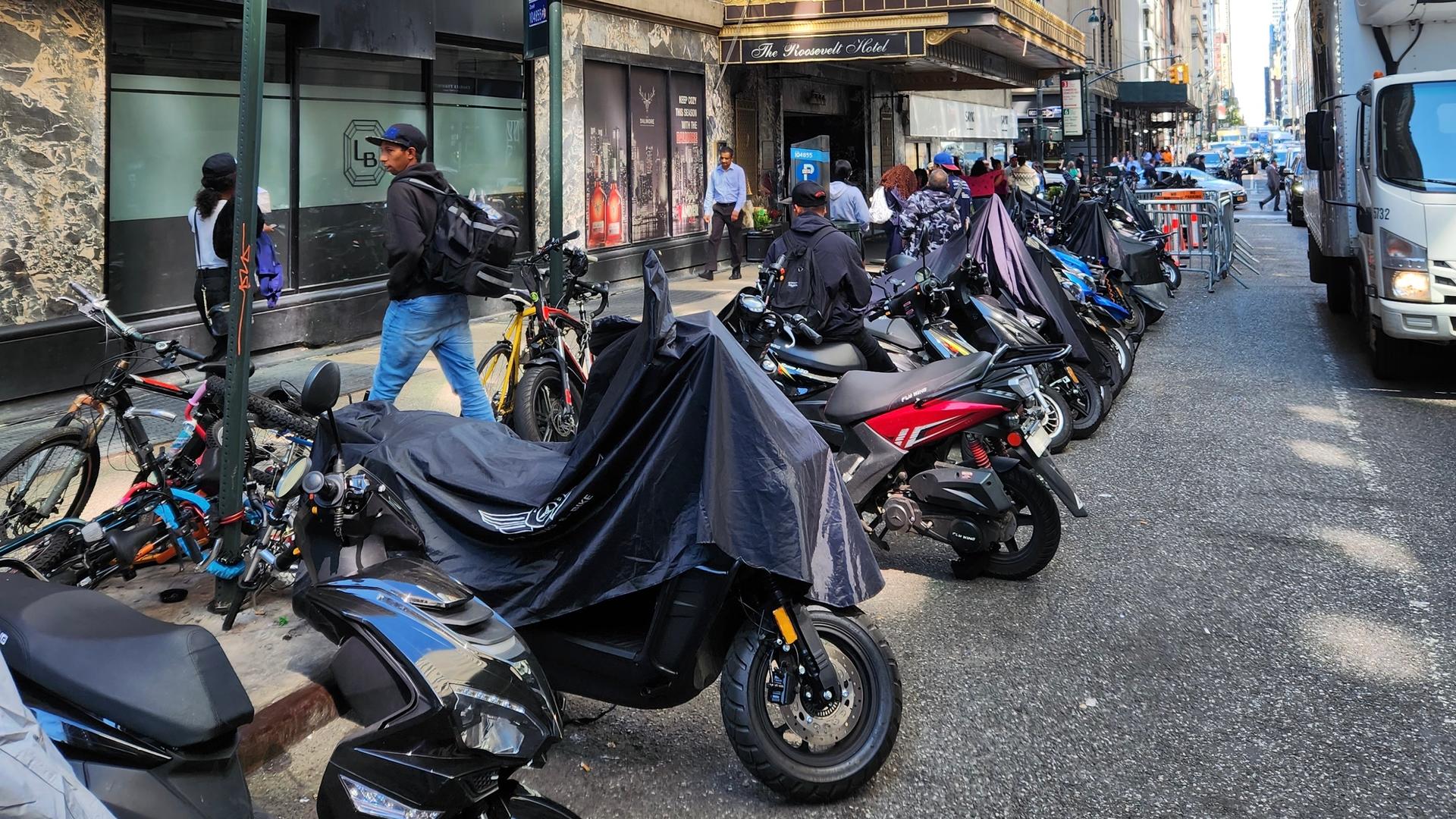 mopeds and motorbikes lined up outside of a hotel