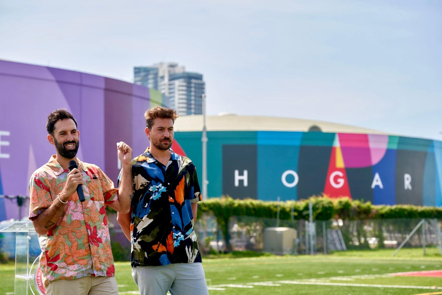 Two men in colorful shirts standing infront of color murals