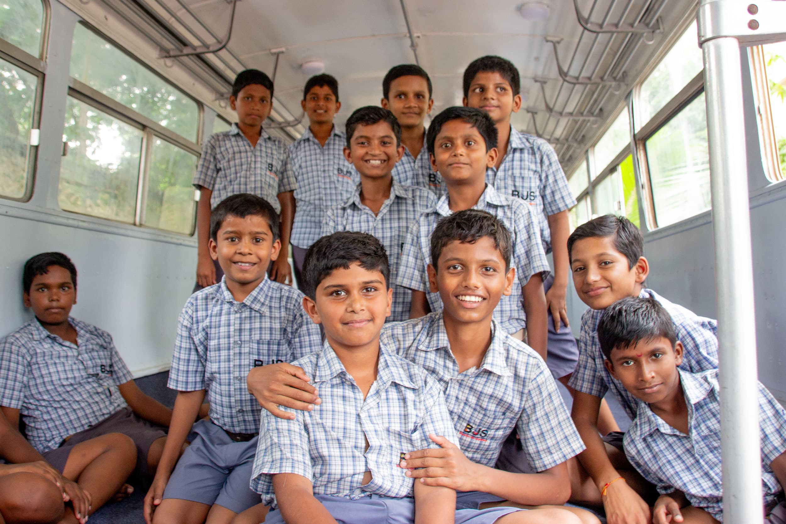 Students at BJS pose inside a decommissioned bus available as a play area on campus.