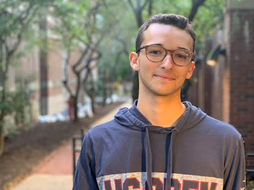 Portrait of a young white male wearing glasses and a navy hoodie