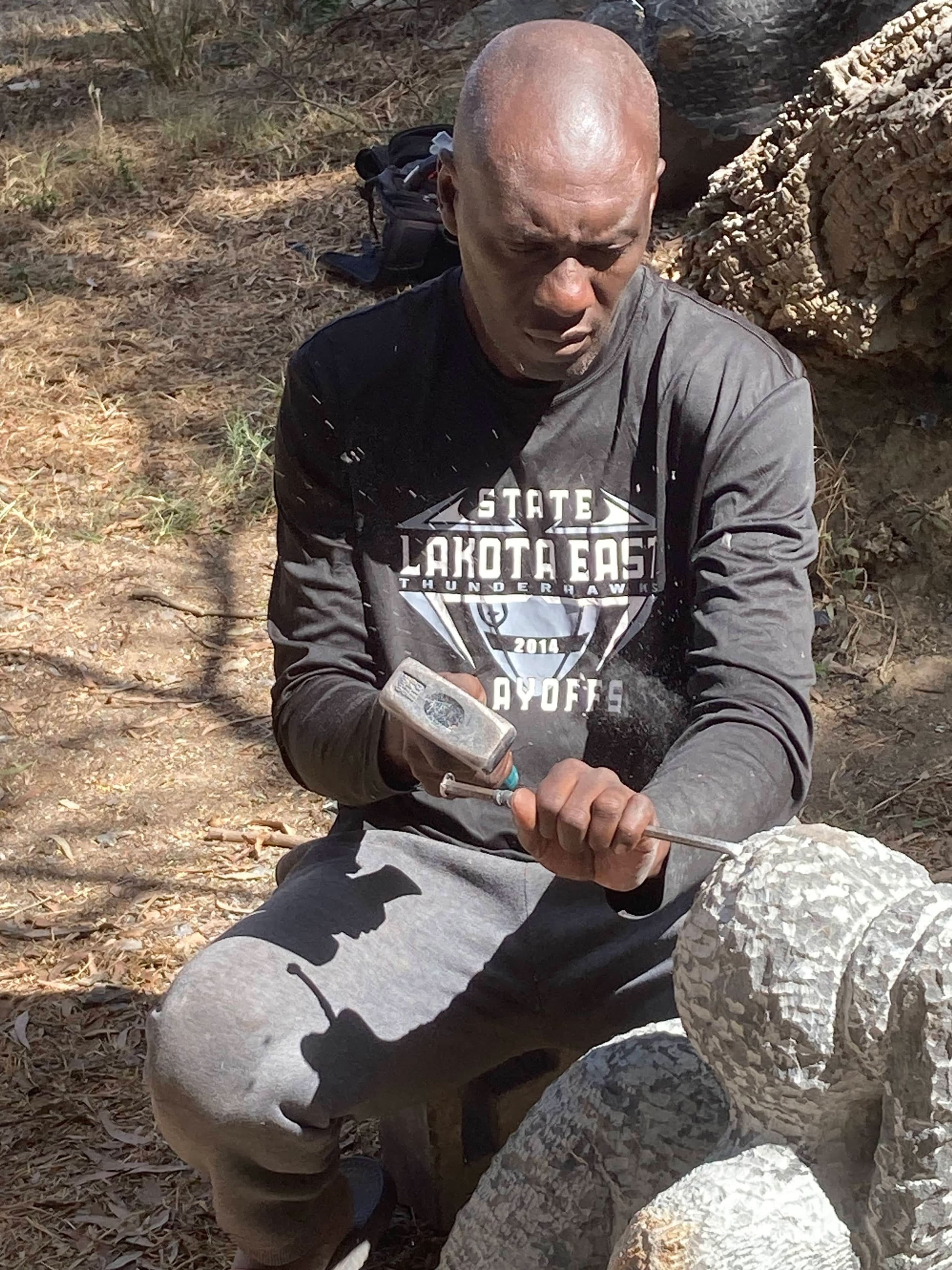 Artist Leo Berekayi uses simple tools to carve into stone to create his sculpture.