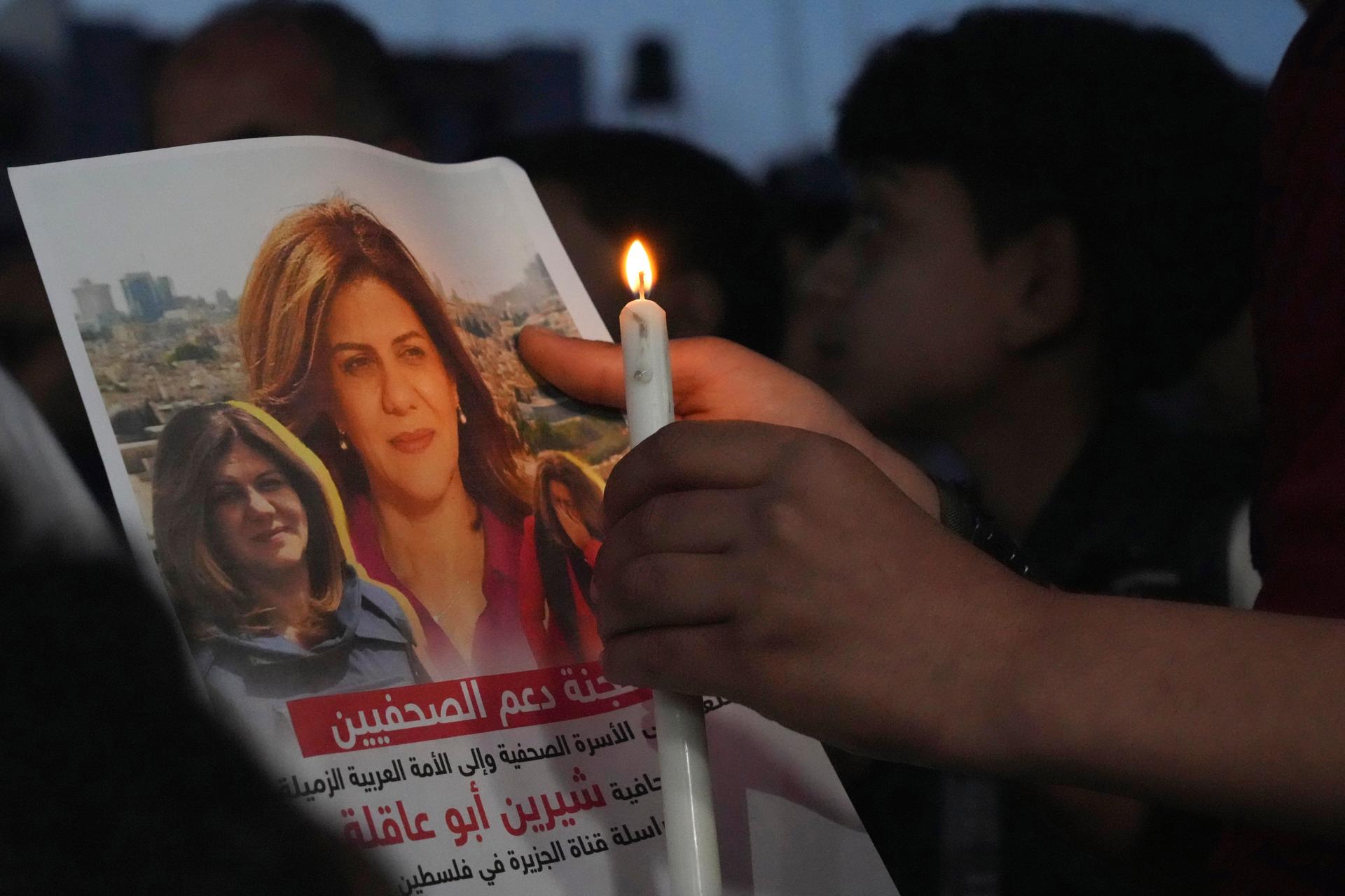 A Palestinian holds a light candle and a picture of slain Al Jazeera journalist Shireen Abu Akleh, to condemn her killing, in front of the office of Al Jazeera network, in Gaza City, May 11, 2022.