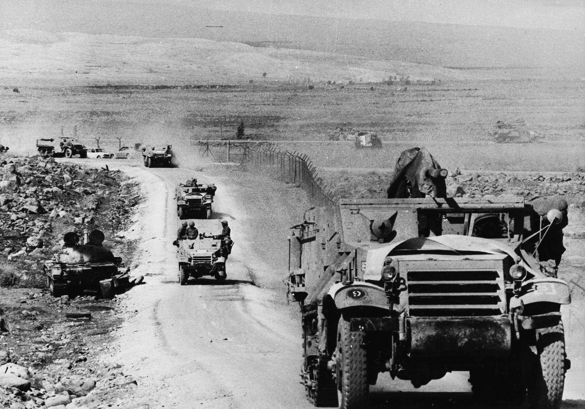 Photo showing tanks and jeeps rolling through a desert