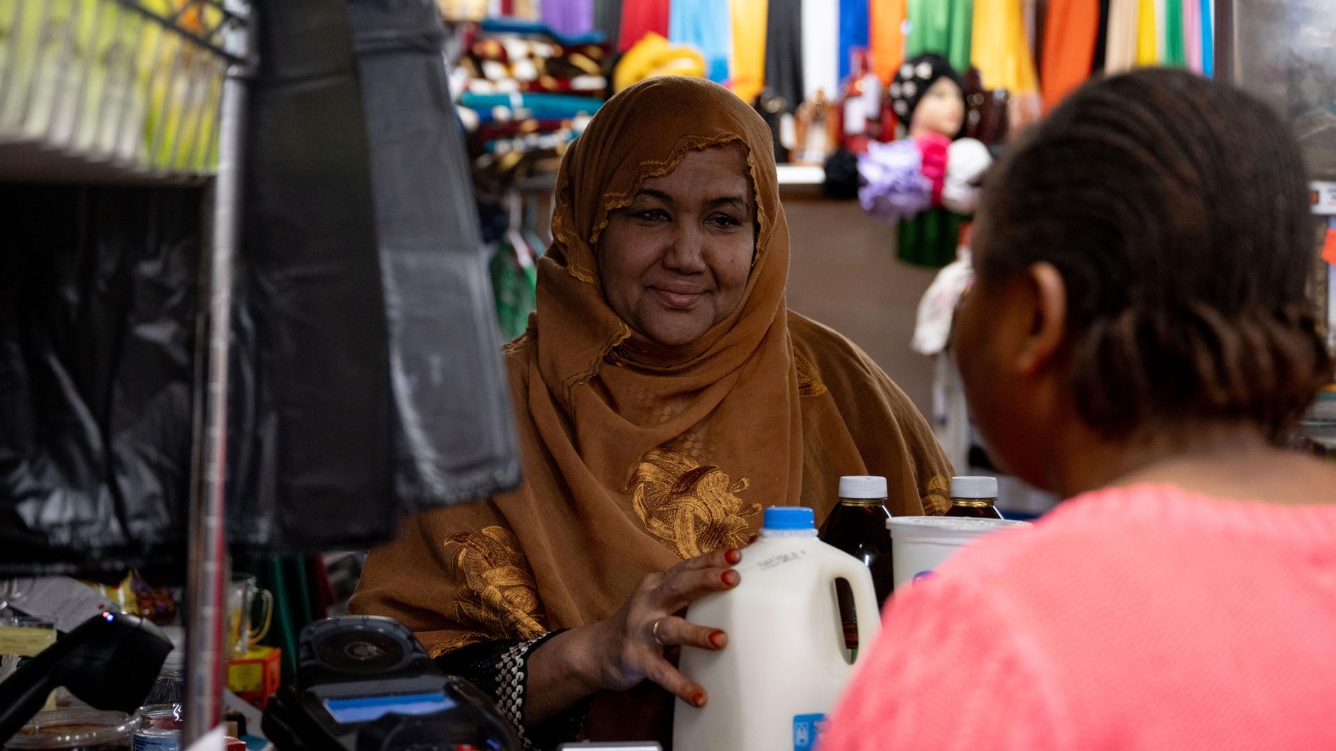Shukri Abasheikh, owner of Mogadishu Store, helps customer Gracia Mbula with a purchase in her store in Lewiston, Maine, on Monday, Oct. 30, 2023.