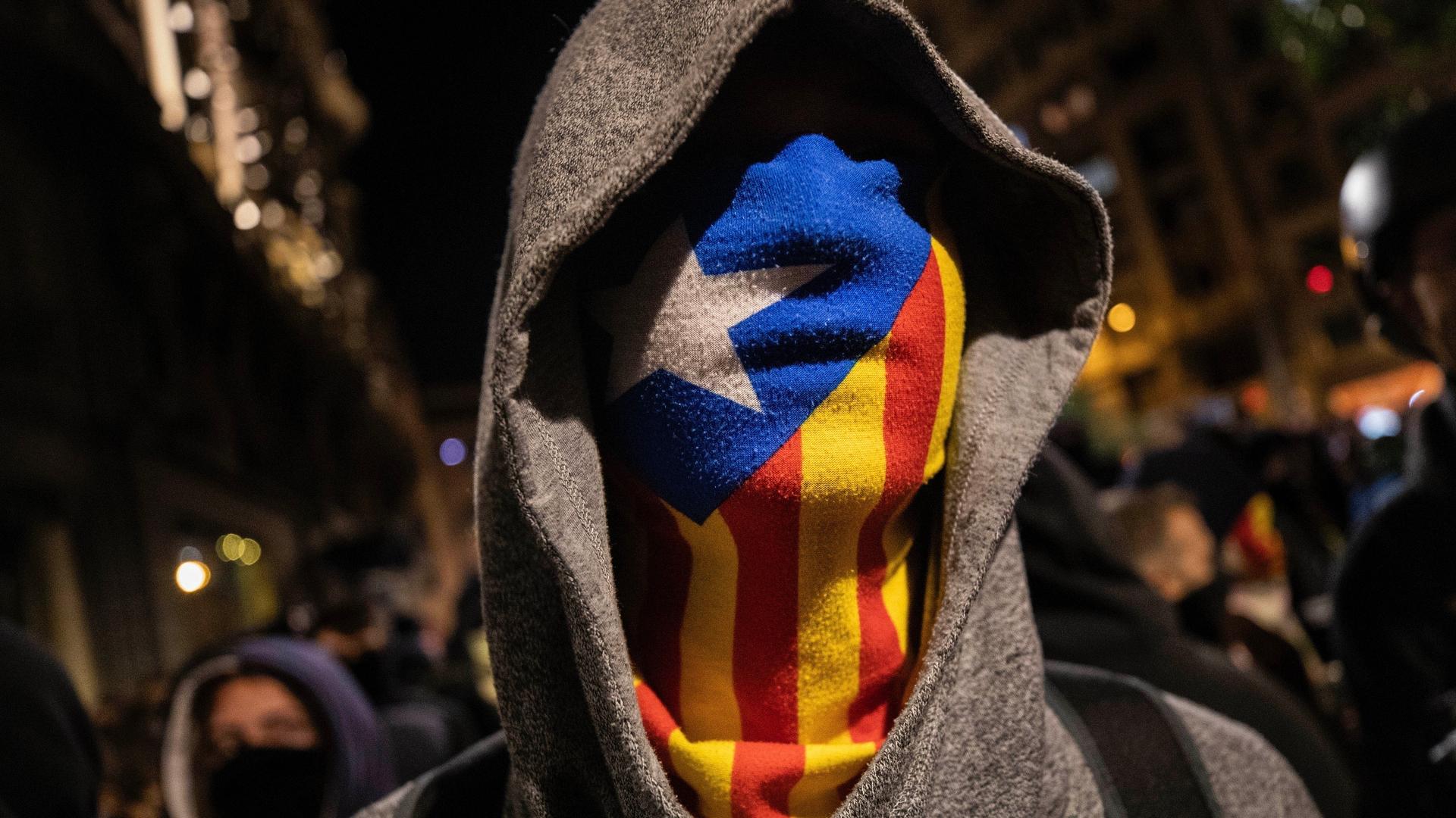 A Catalan pro-independence protestor wearing an Estelada, or Catalan independence mask, stands in front of police, not seen, during a protest in Barcelona, Saturday, Oct. 26, 2019.