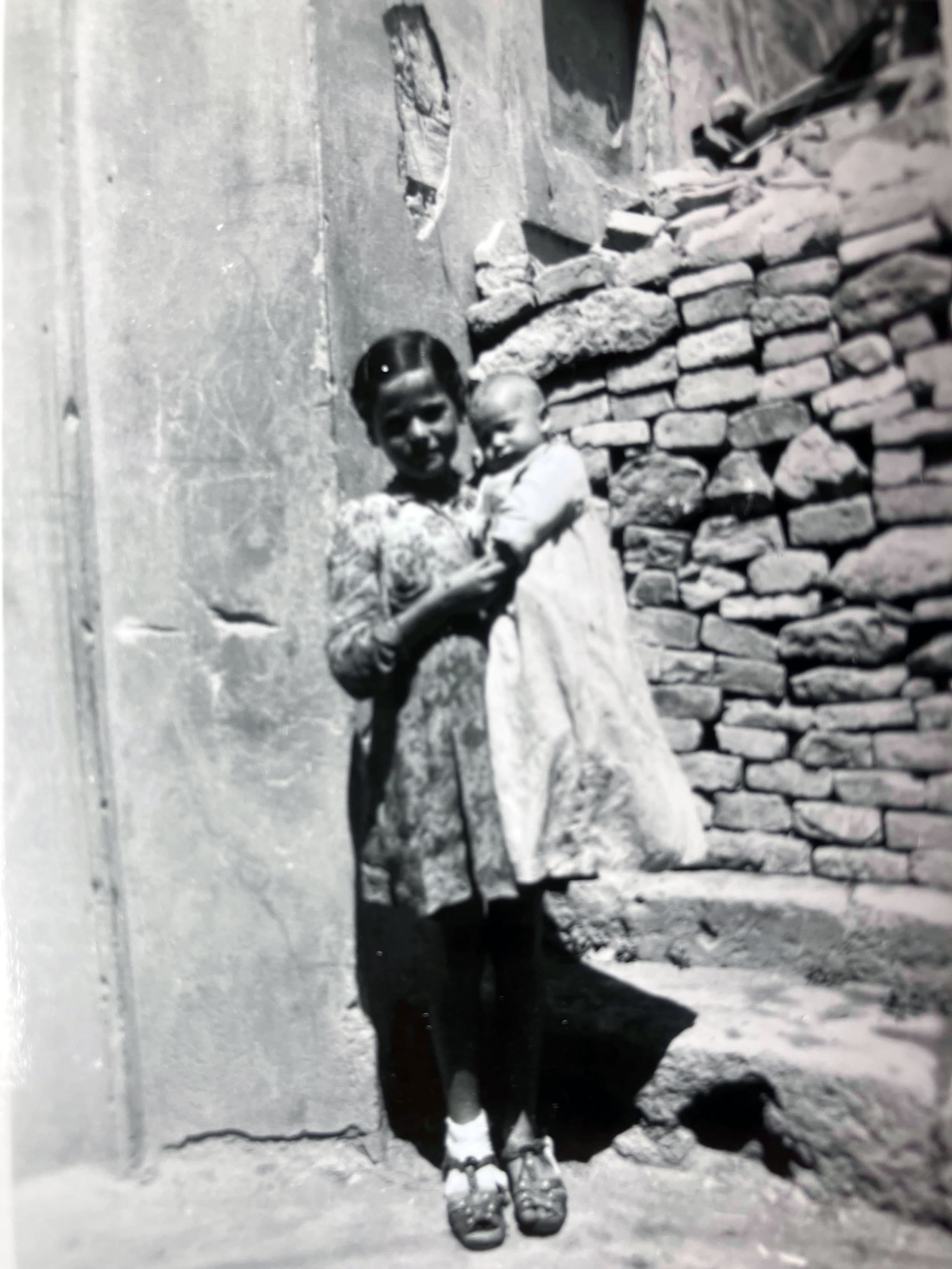 A young girl holds a baby to her chest in a village in southern Italy, 1944.