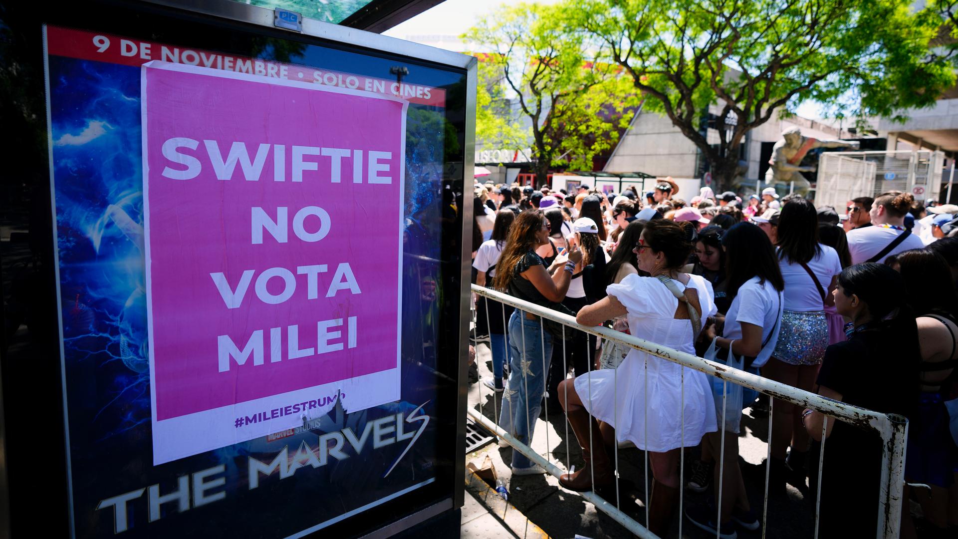 A pink sign in the forefront of a largely female crowd that reads in Spanish "Swiftie No Vota Milei"