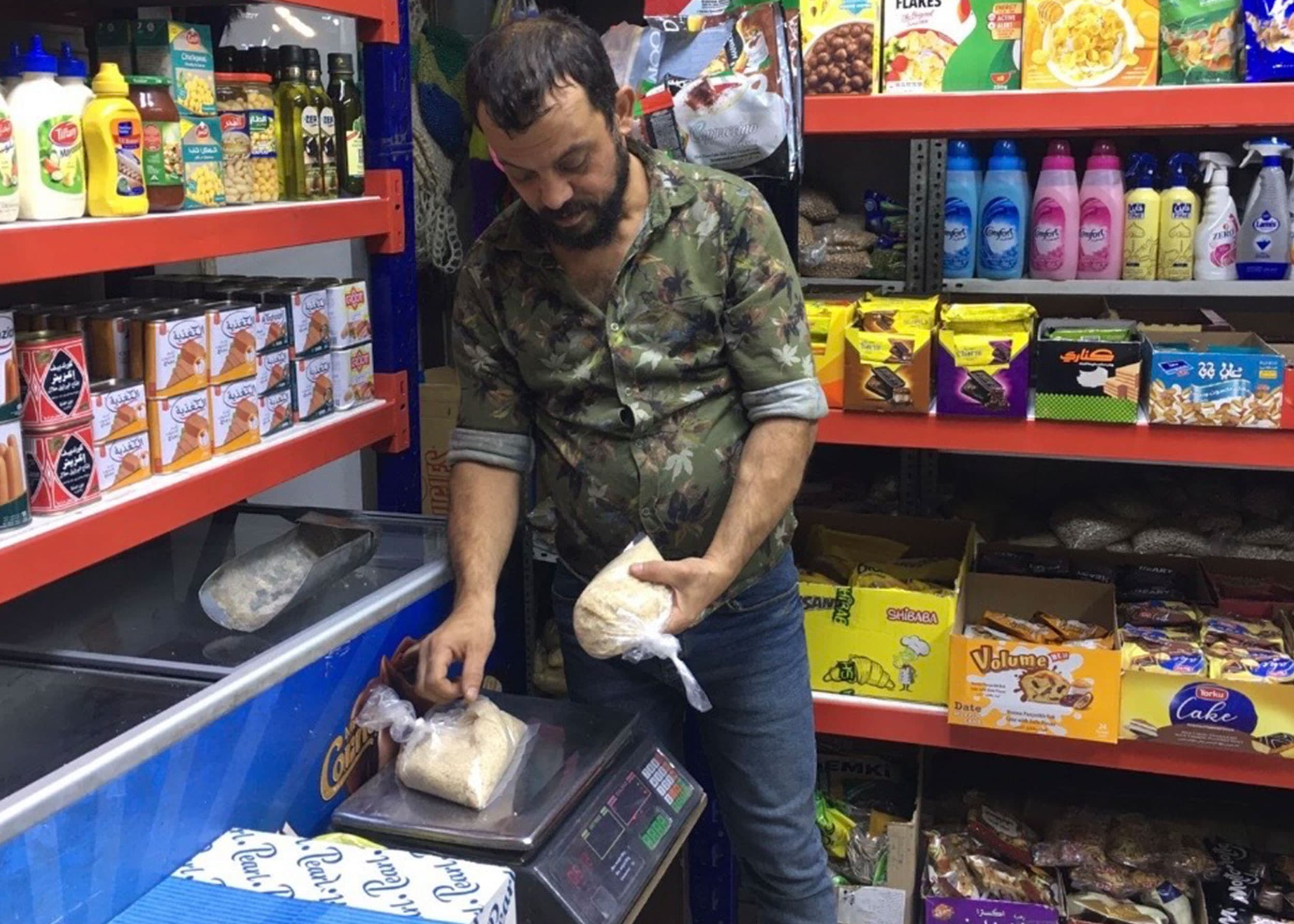Ahmed Salim, the manager of a store at Al-Warda Market, weighs packets of rice, central Baghdad, Sept. 24, 2023.