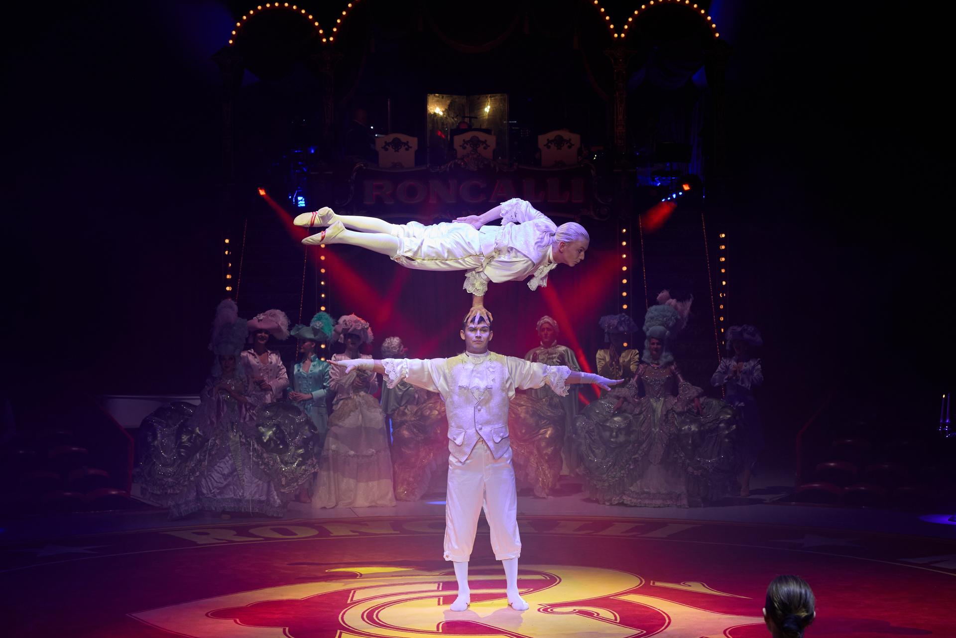 Two people balancing on each other in white outfits