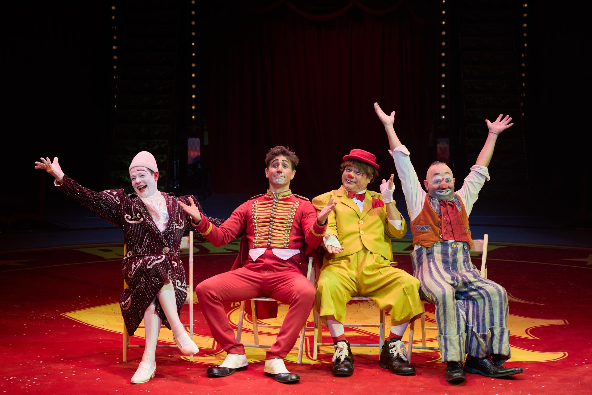 four clown sitting on a red stage