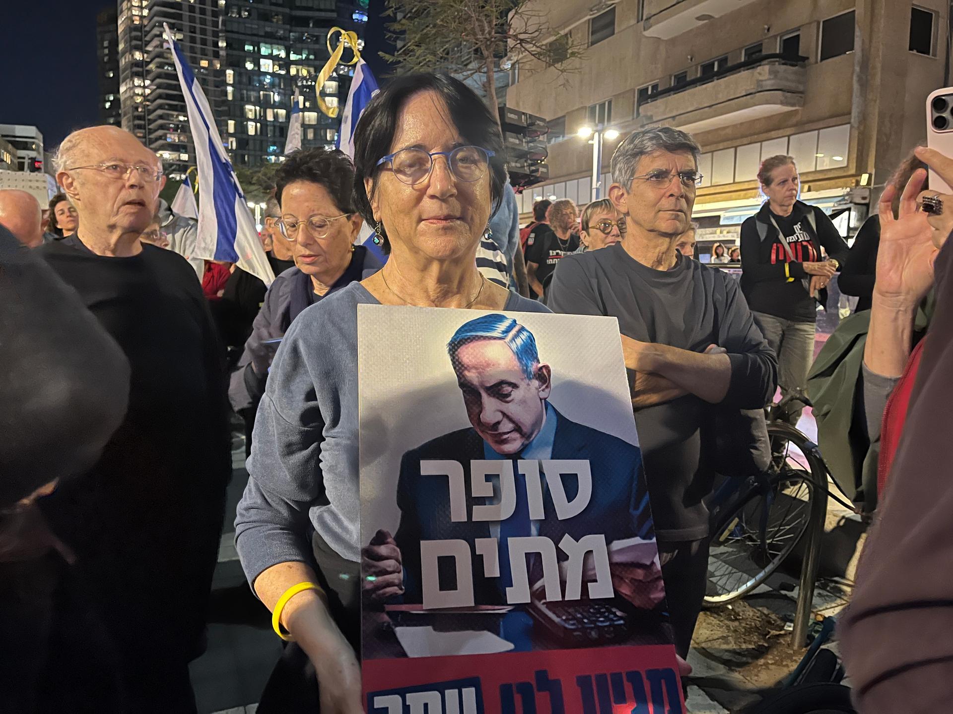 A woman holds an anti-government sign with a photo of Israeli Prime Minister Benjamin Netanyahu