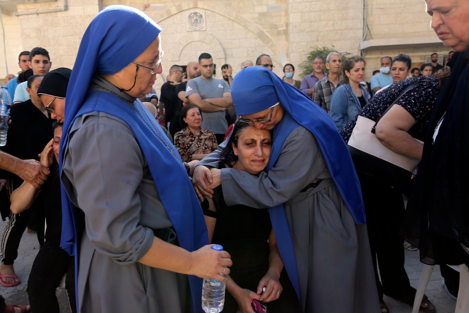 Nuns comfort a Palestinian woman as she mourns the death of a relative, killed in Israeli airstrikes that hit a church, during a funeral service in Gaza City, Oct. 20, 2023.