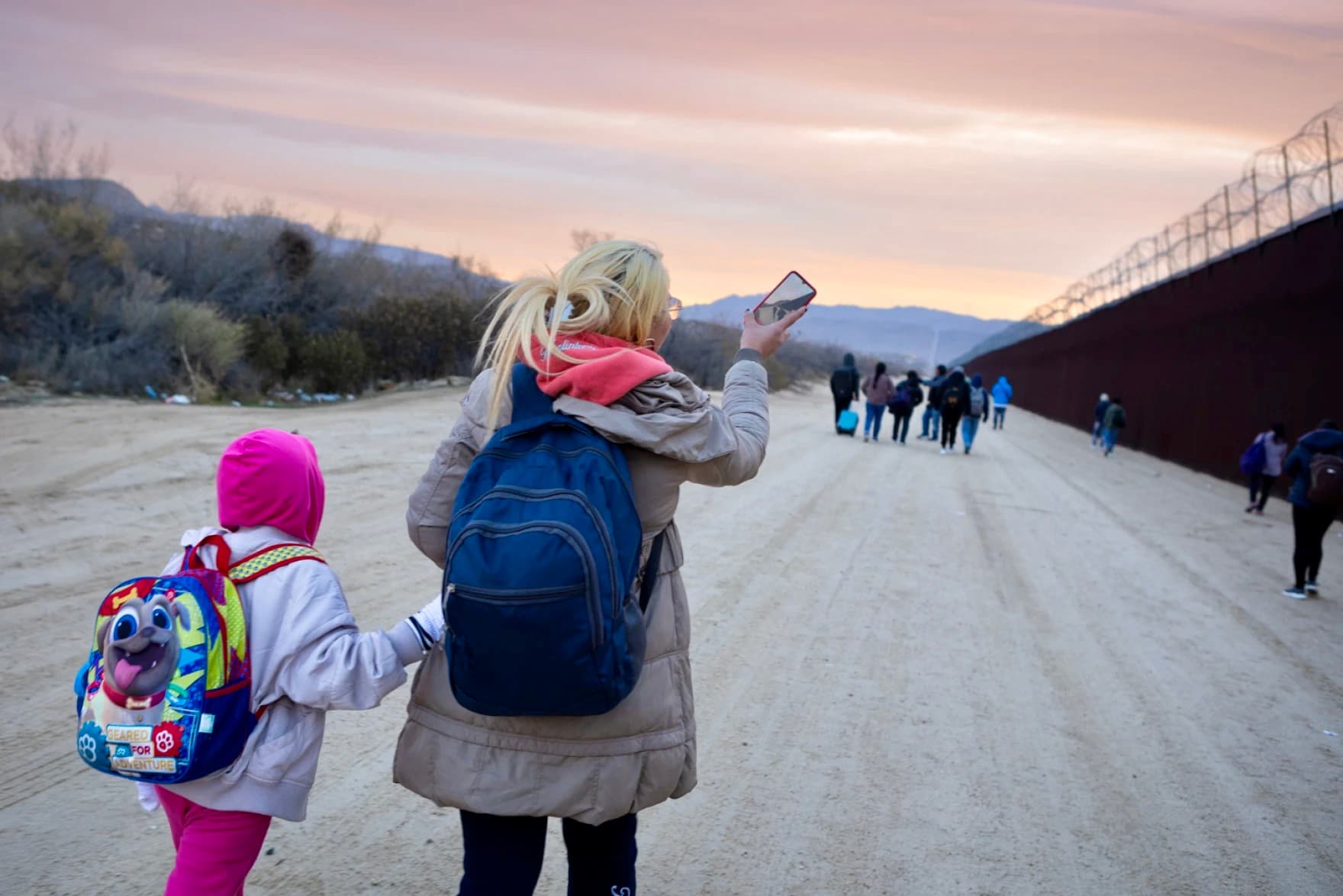 The back side of a woman and her daughter, both wearing winter wear, walking