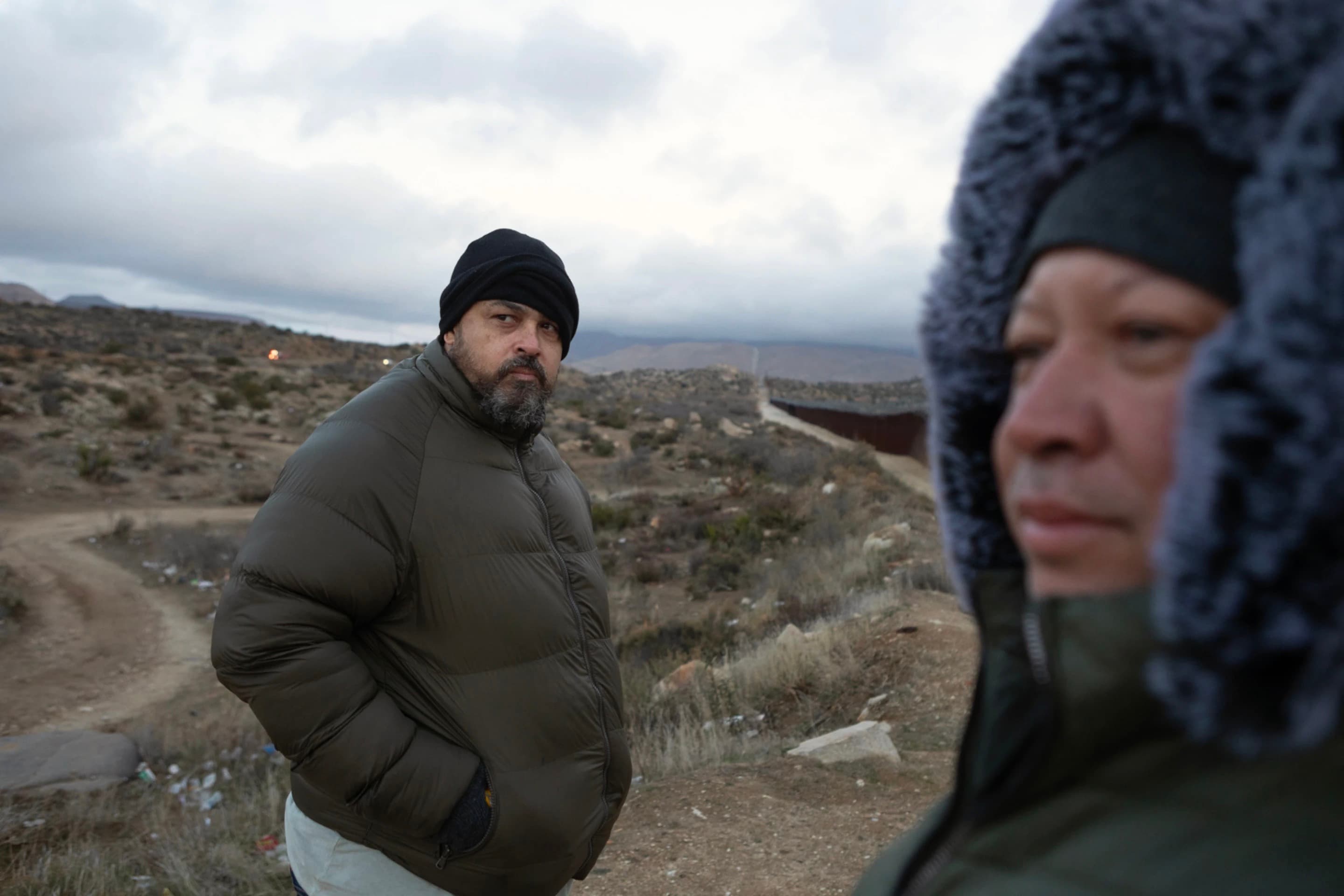 Two men from Brazil look out into the surrounding landscape from a hill.