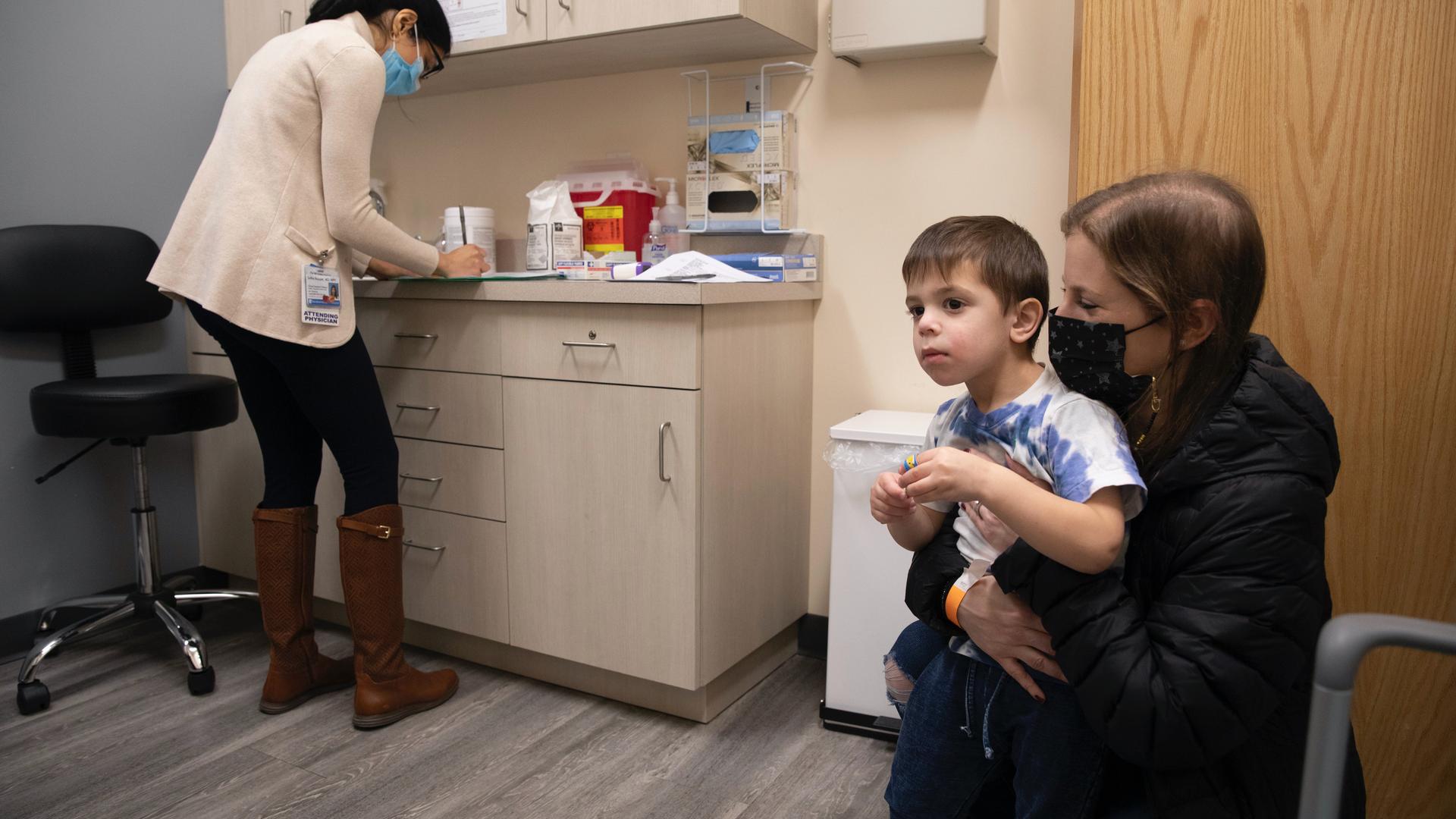 parent holds child in doctor’s office
