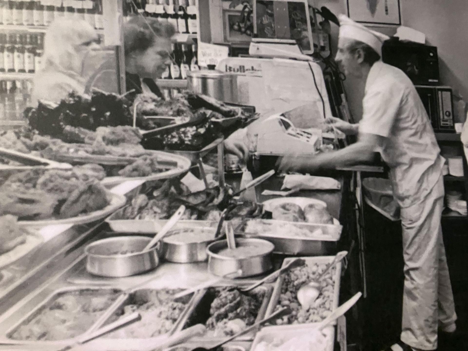 One long wall of the exhibit features portraits and photos of deli workers and owners in action behind the counter, serving discerning customers.
