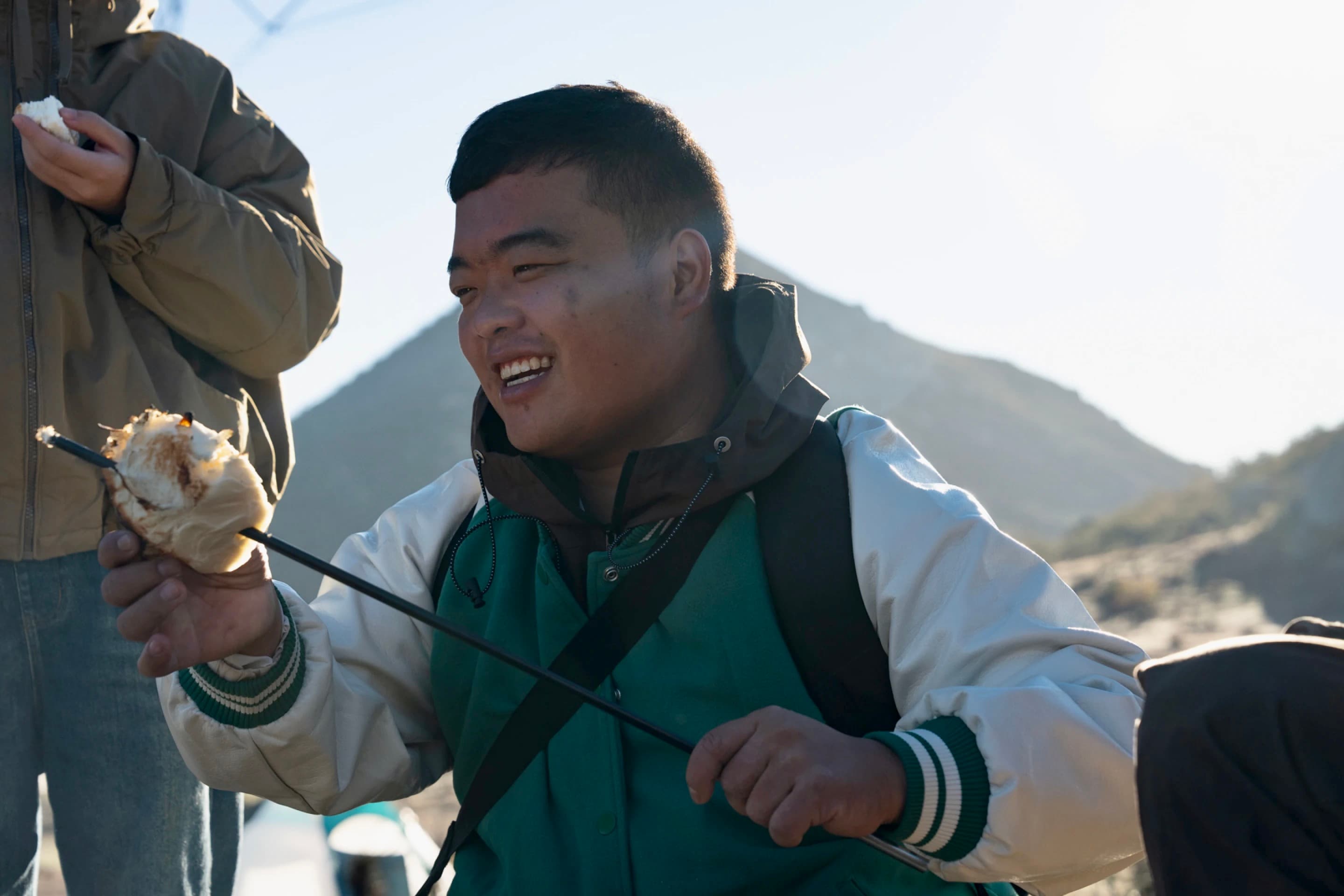 A Chinese migrant grills a bun on a tent pole
