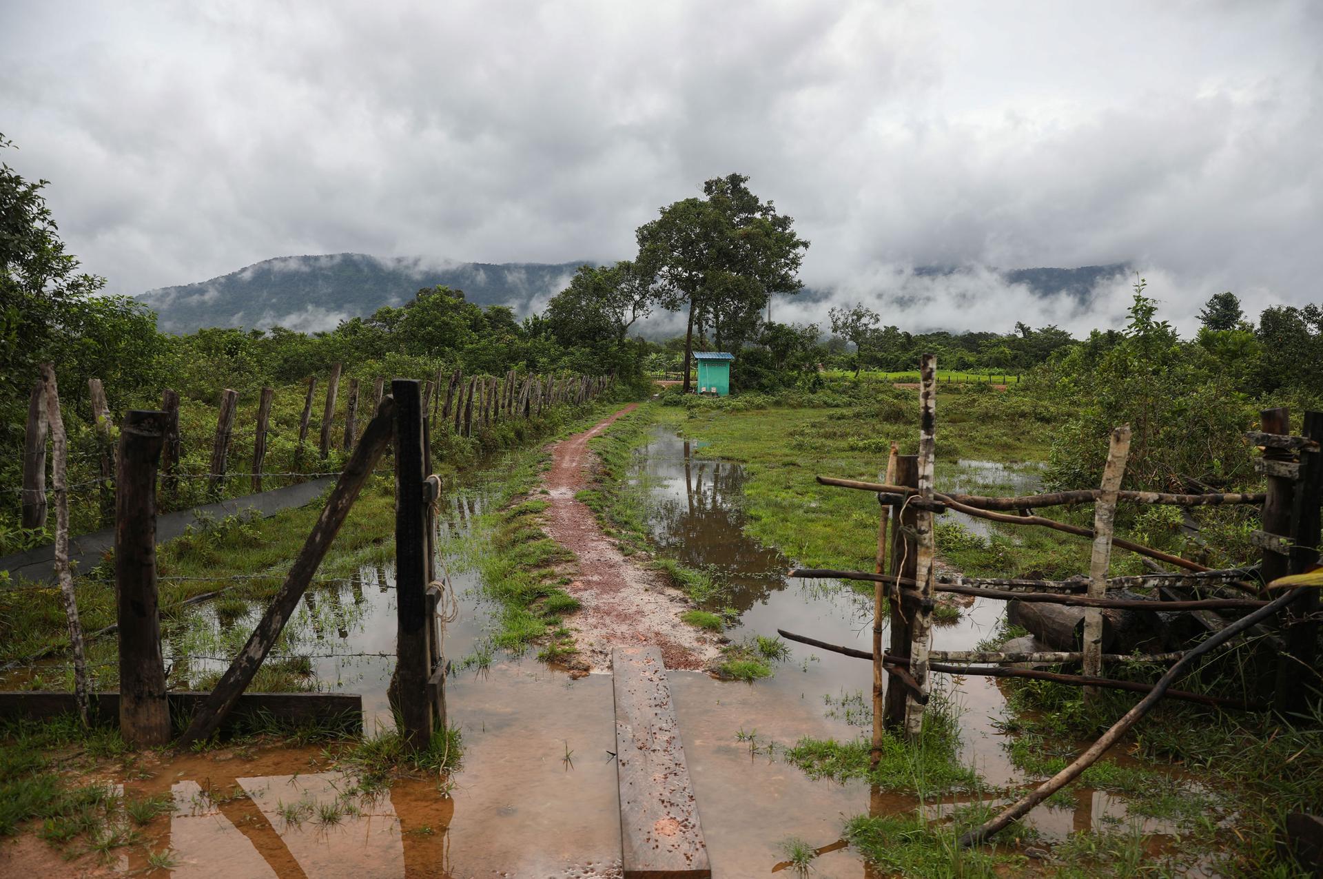 A bathroom, supported by the Southern Cardamom REDD+ Project within the national park, is visible from the rain-drenched gate of a home in Samraong village.