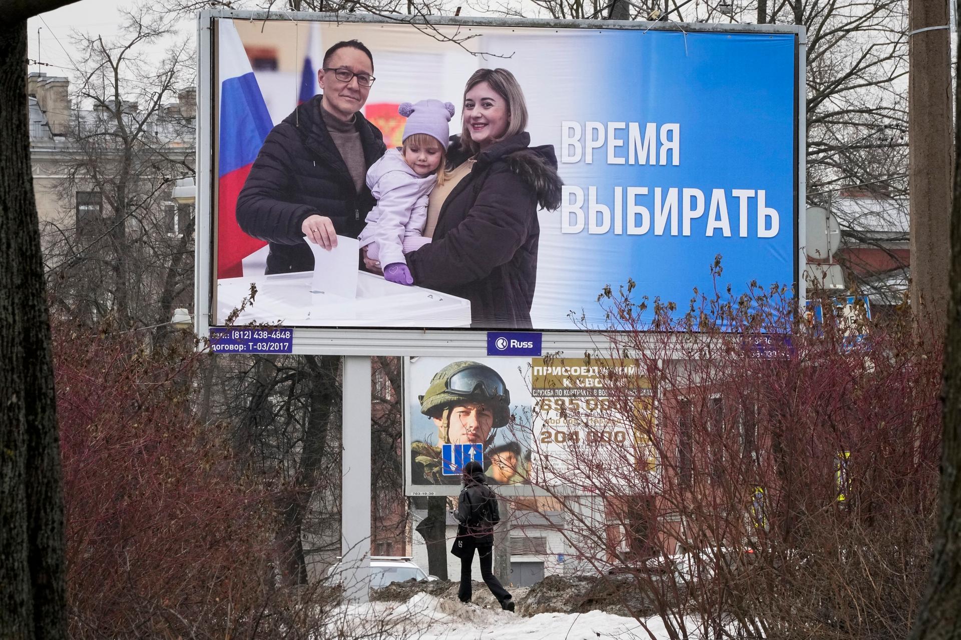 A woman walks past a billboard promoting the upcoming presidential election with the words in Russian 