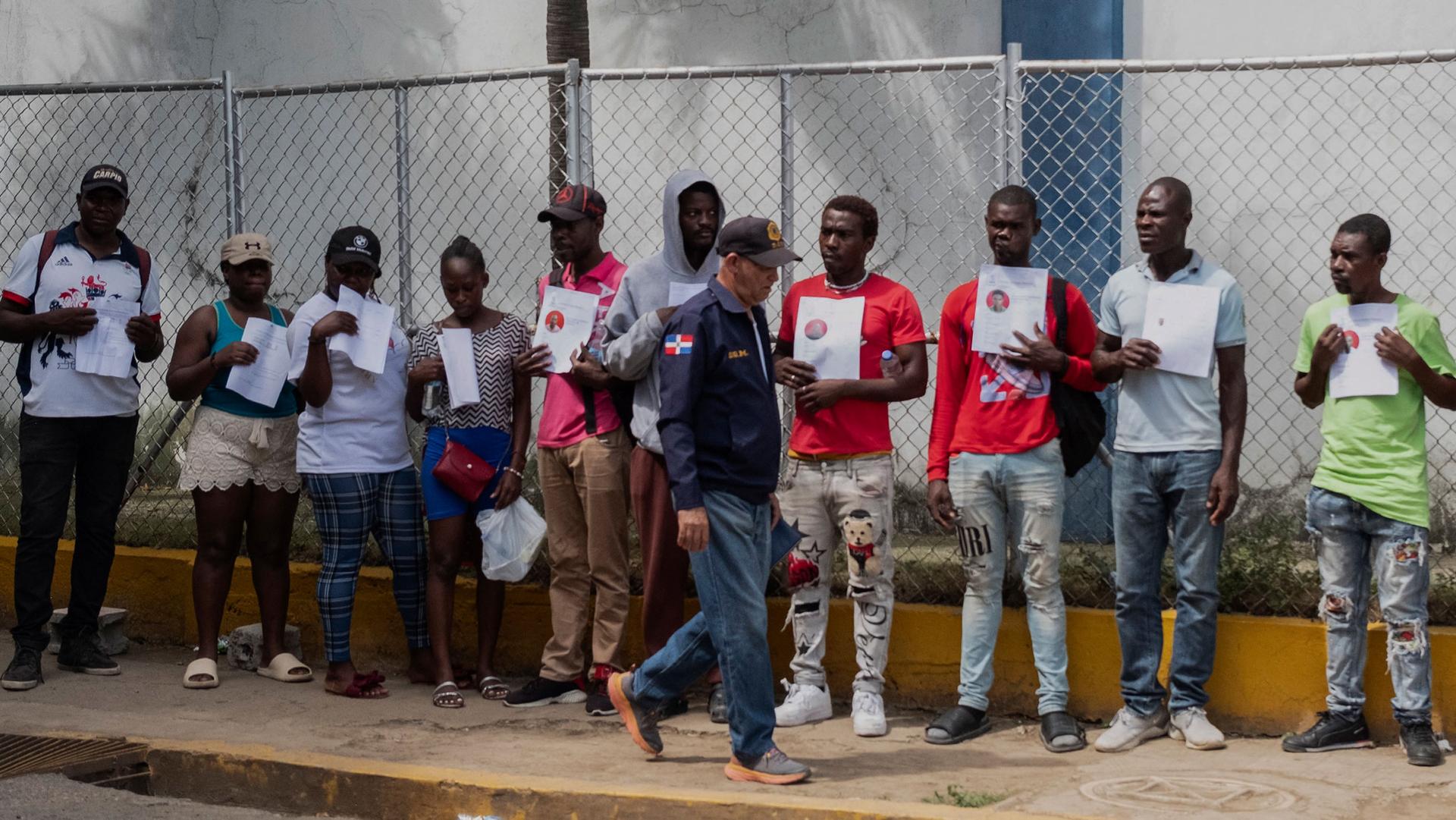 Haitians who were detained hold up their immigration status documents to prove they have work permits, in Haina, Dominican Republic, March 16, 2024.