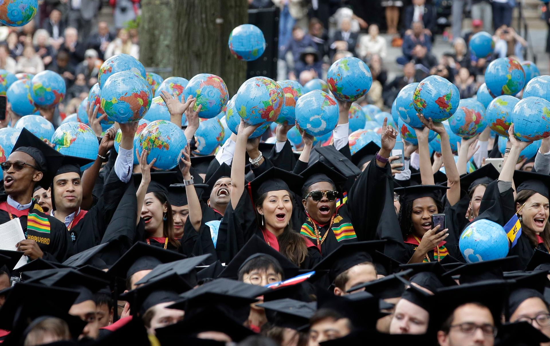 Graduates of Harvard's John F. Kennedy School of Government hold aloft inflatable globes as they celebrate graduating during Harvard University's commencement exercises, May 30, 2019, on the schools campus in Cambridge, Mass.