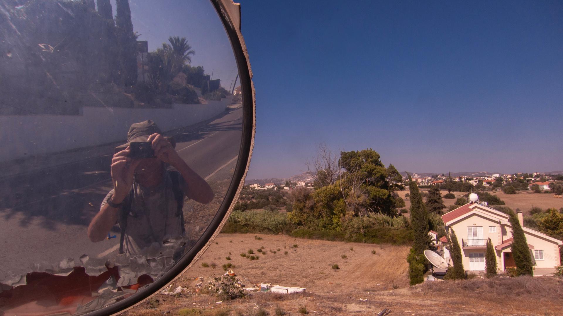 Man taking photo of self in mirror with a desert background