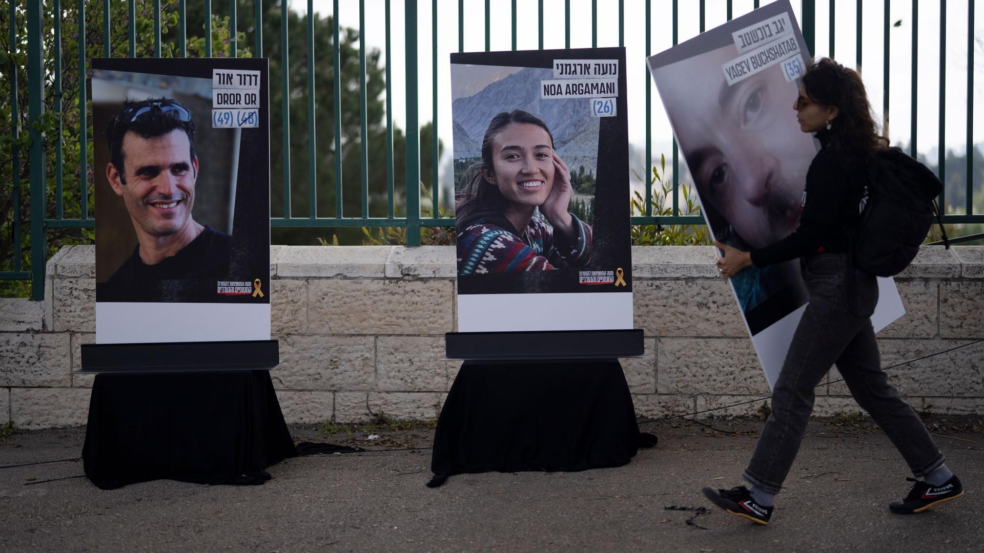 A woman carrying a poster of person kidnapped on Oct. 7 during the cross-border attack by Hamas militants, walks past a poster depicting Israeli hostage Noa Argamani, 26, center, before a protest in Jerusalem, Sunday, April 7, 2024.