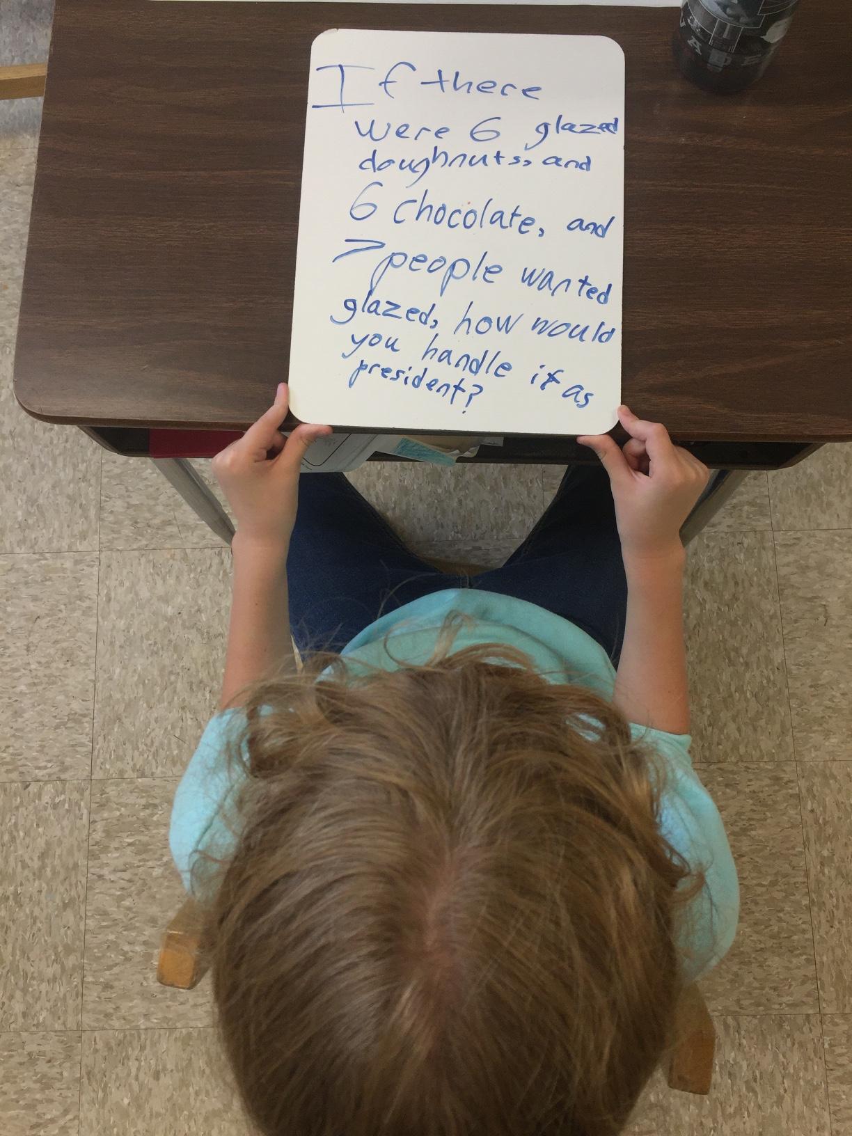 Lily, a second grader at the Circle School in San Antonio, looks down at her prepared question for her class president candidates.