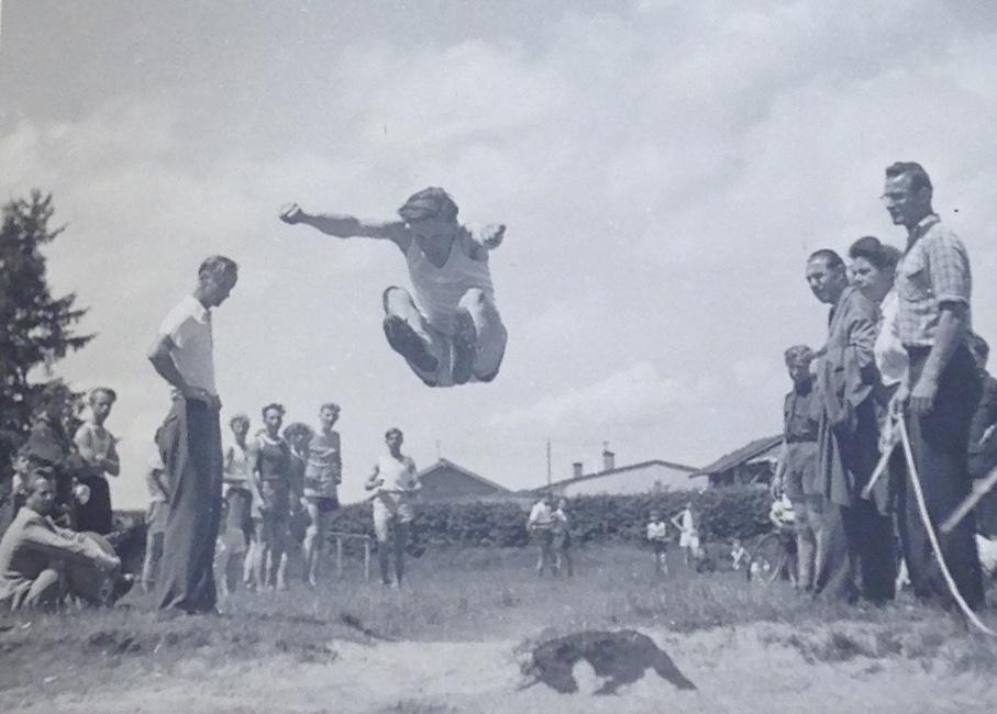 A young man in mid-air while he competes in the long jump at a competition of refugee athletes in Germany during World War II