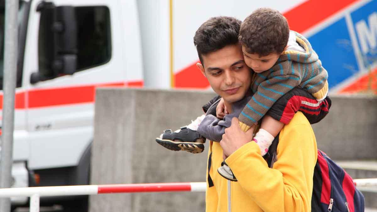 Ahmed and his family came to Munich from Syria. He is carrying his young cousin.  He came to Germany “for studying, good work, and to get married and have a baby from [a] German.”