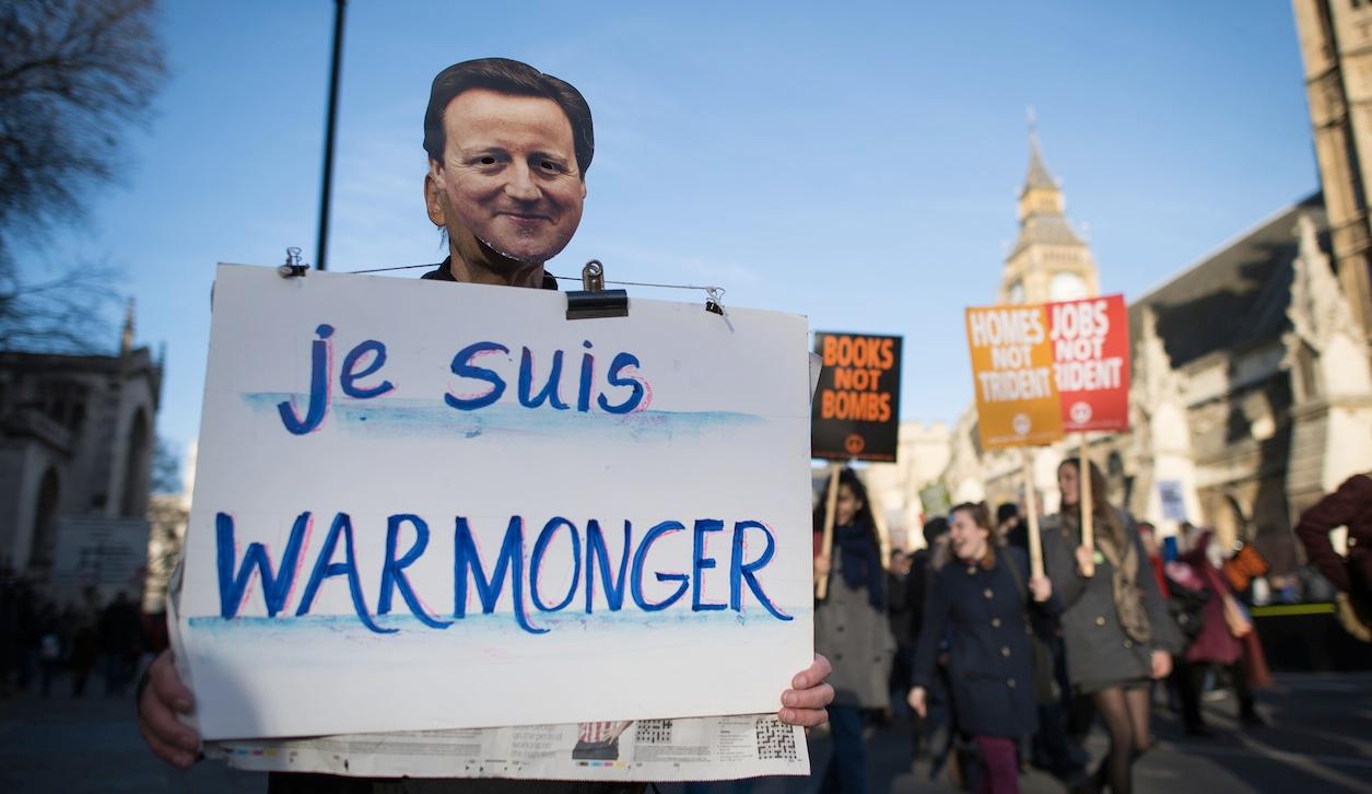 An anti-nuclear protester wearing a mask depicting British Prime Minister David Cameron holds a sign that reads 'I am warmonger' during a protest in central London on January 24, 2015, calling for the British government to abolish the Trident nuclear miss