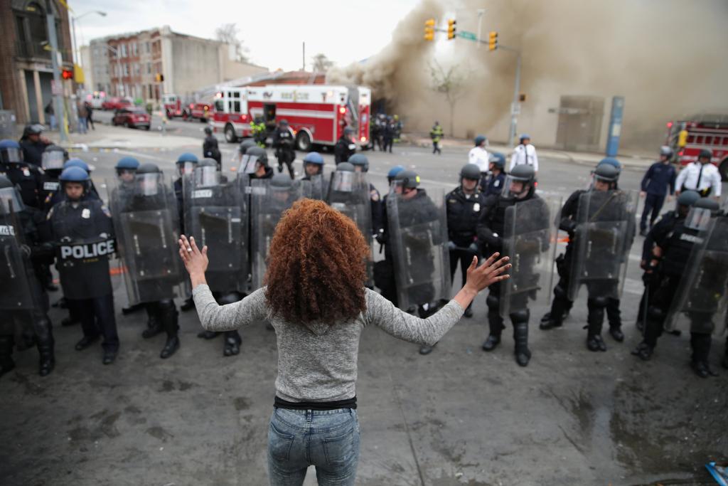 A female protester stands in front of riot police in Baltimore.