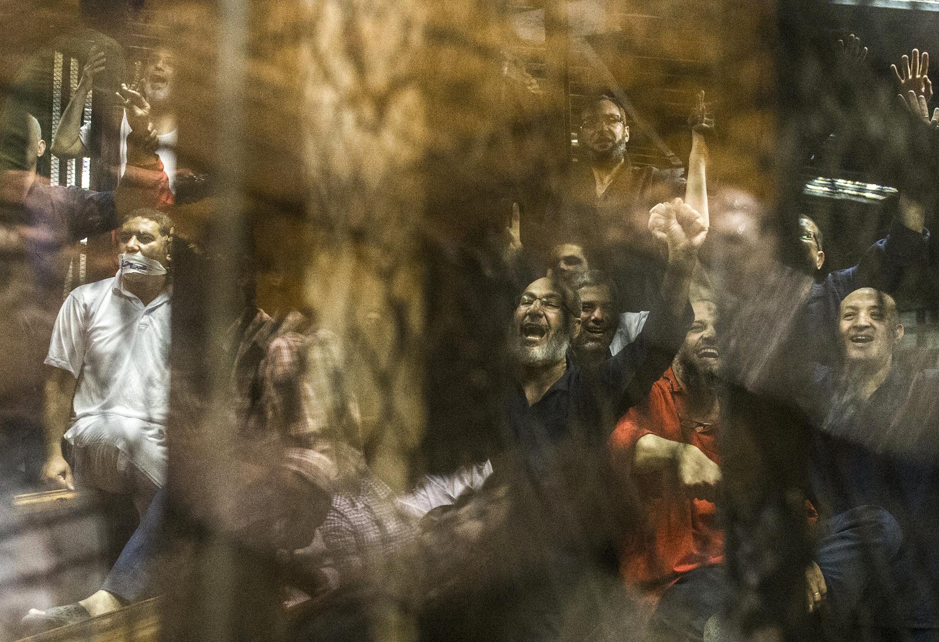The Muslim Brotherhood's Safwat Hegazy (C) shouts from behind the defendants' cage as a judge reads out the verdict sentencing him and more than 100 other defendants to death on May 16, 2015 at the police academy in Cairo.