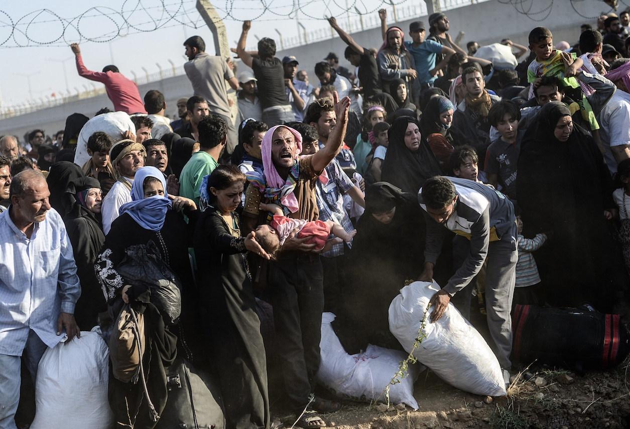 Syrians fleeing the war wait to enter Turkey near the Turkish border crossing at Akcakale