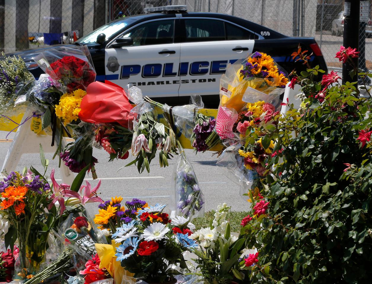 A police car is seen near flowers on a road leading to the Emanuel African Methodist Episcopal Church the morning after a mass shooting in Charleston, South Carolina, June 18, 2015.